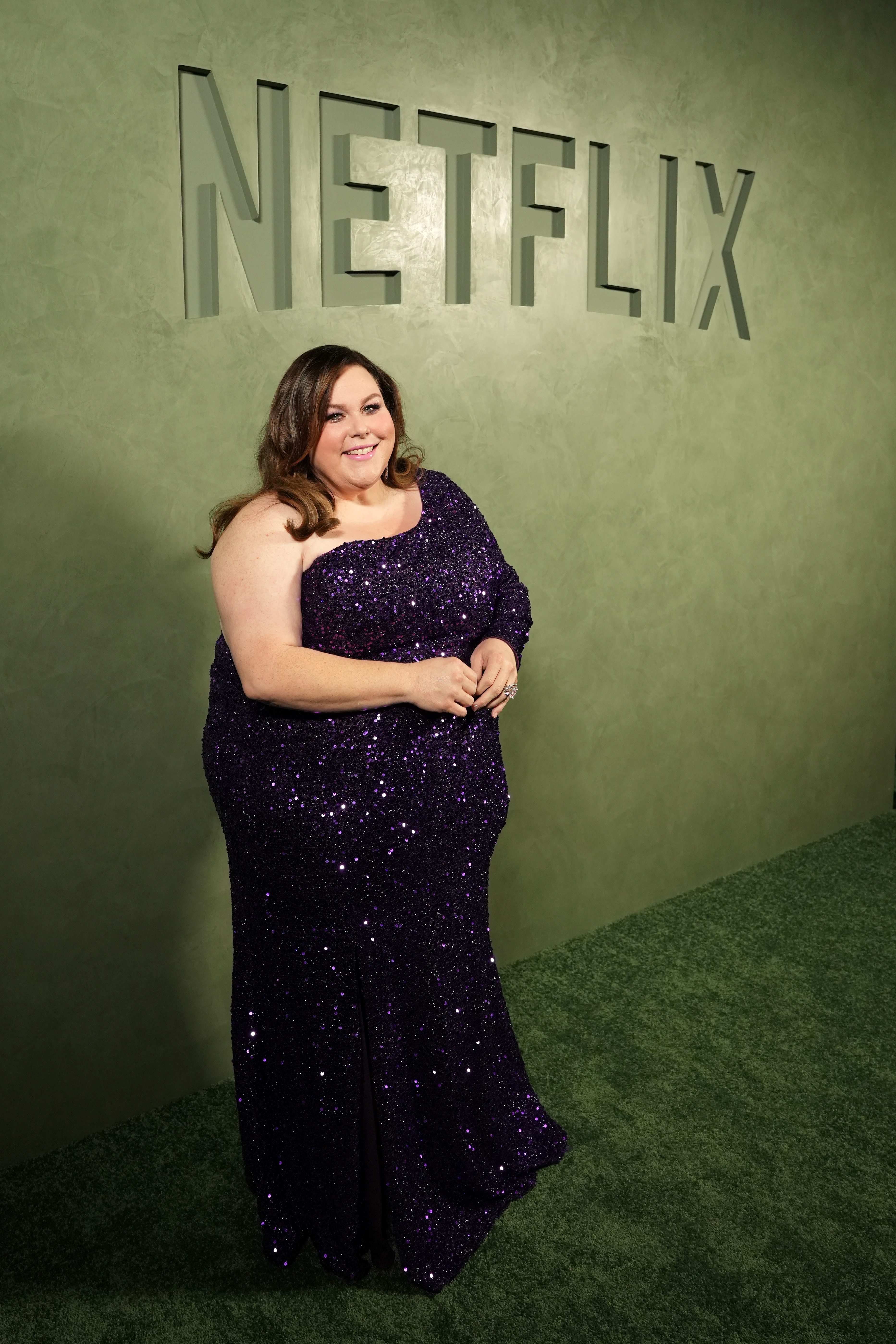 Chrissy Metz poses on the Creative Arts Emmys red carpet in a flowing emerald-green gown with a sheer train. She completes the look with delicate jewelry, soft makeup, and a warm smile. | Source: Getty Images