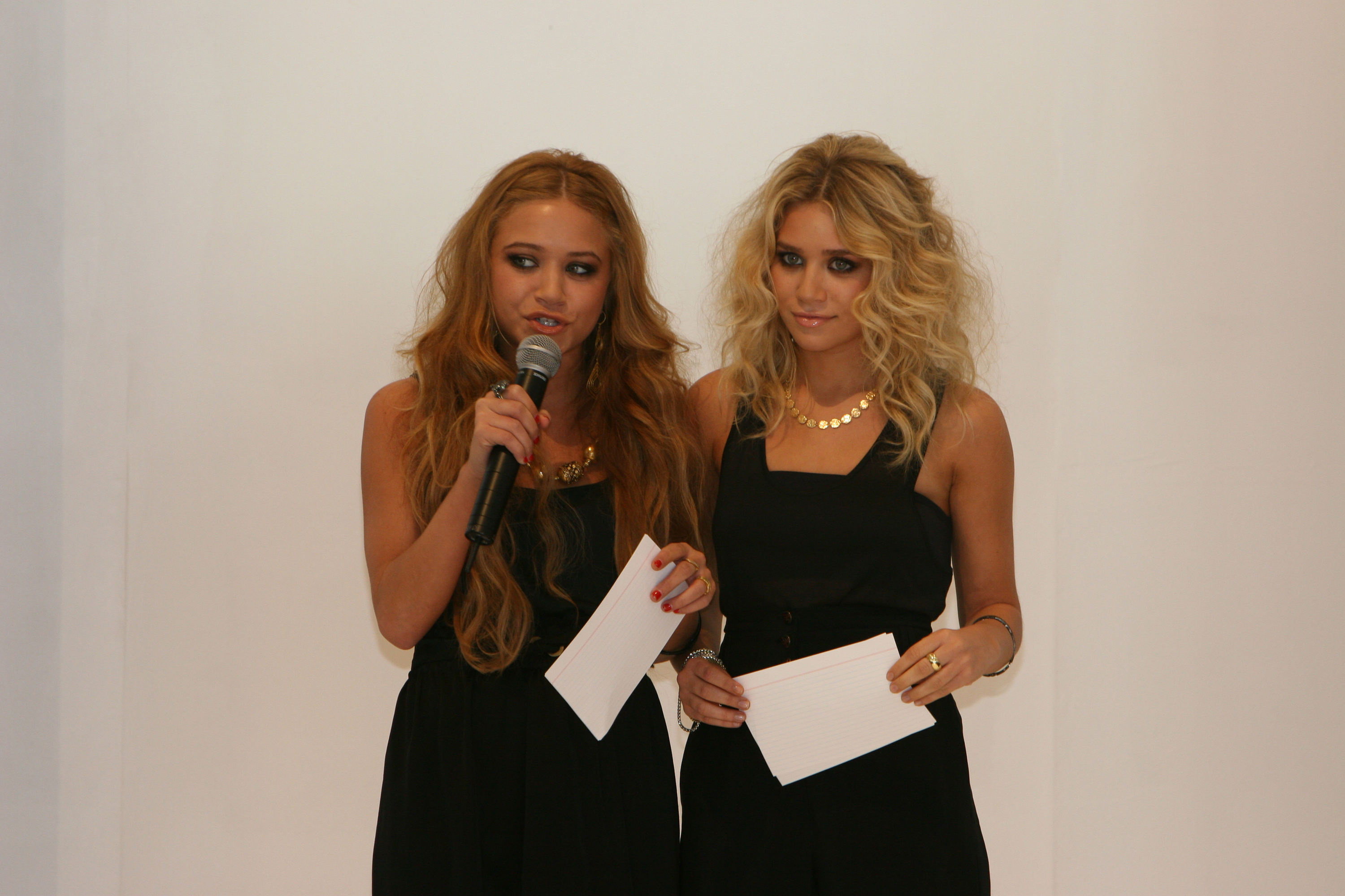 Executive authority and sleek young-adult maturity defined the 19-year-olds at a Sydney event on February 19, 2006, their poised faces framed by distinct hairstyles, one with soft golden-brown waves and the other with loose blonde curls, worn with sharp black evening wear and gold coin pendants.