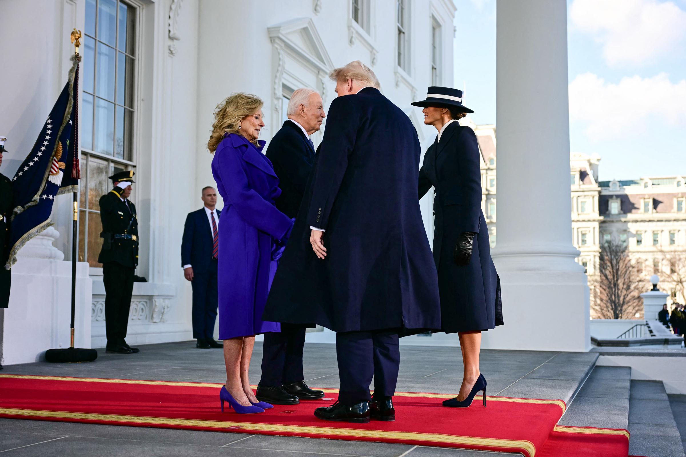 Incoming First Lady Melania Trump arrives at the White House alongside President-elect Donald Trump on Inauguration Day, January 20, 2025, greeted by President Joe Biden and First Lady Jill Biden before departing for the U.S. Capitol. Making a commanding fashion statement, she wears a custom navy wool coat by Adam Lippes with black leather gloves and a matching wide-brim boater hat by Eric Javits, finishing the sharp silhouette with dark navy pointed-toe stiletto pumps that provide a classic, sky-high lift down the red carpet.