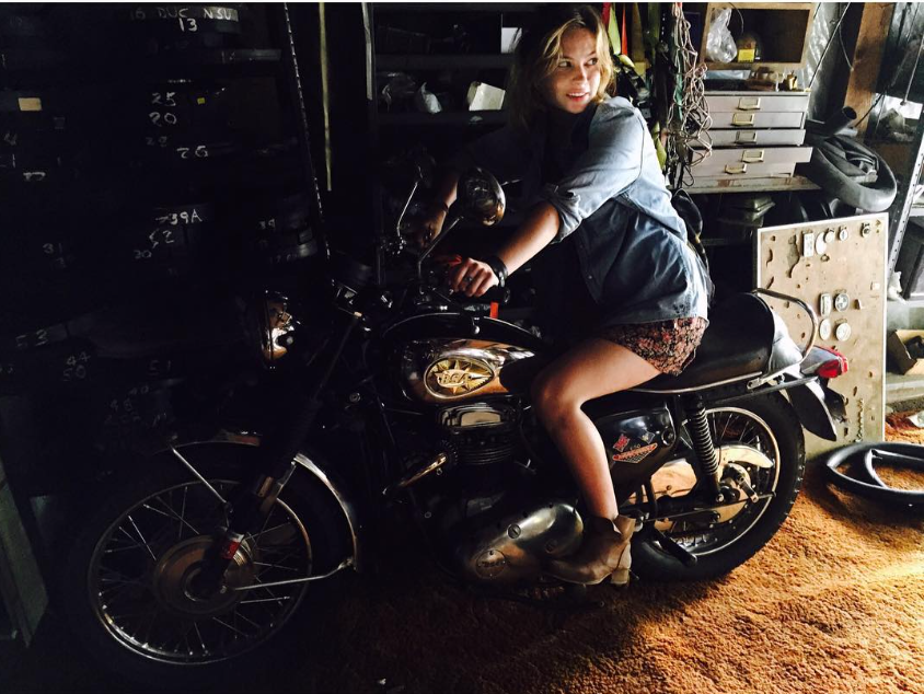 Daveigh Chase smiles while sitting on a motorcycle inside a dimly lit garage in a photo shared in September 2015, about a decade before her death at age 35. | Source: Instagram/daveighc