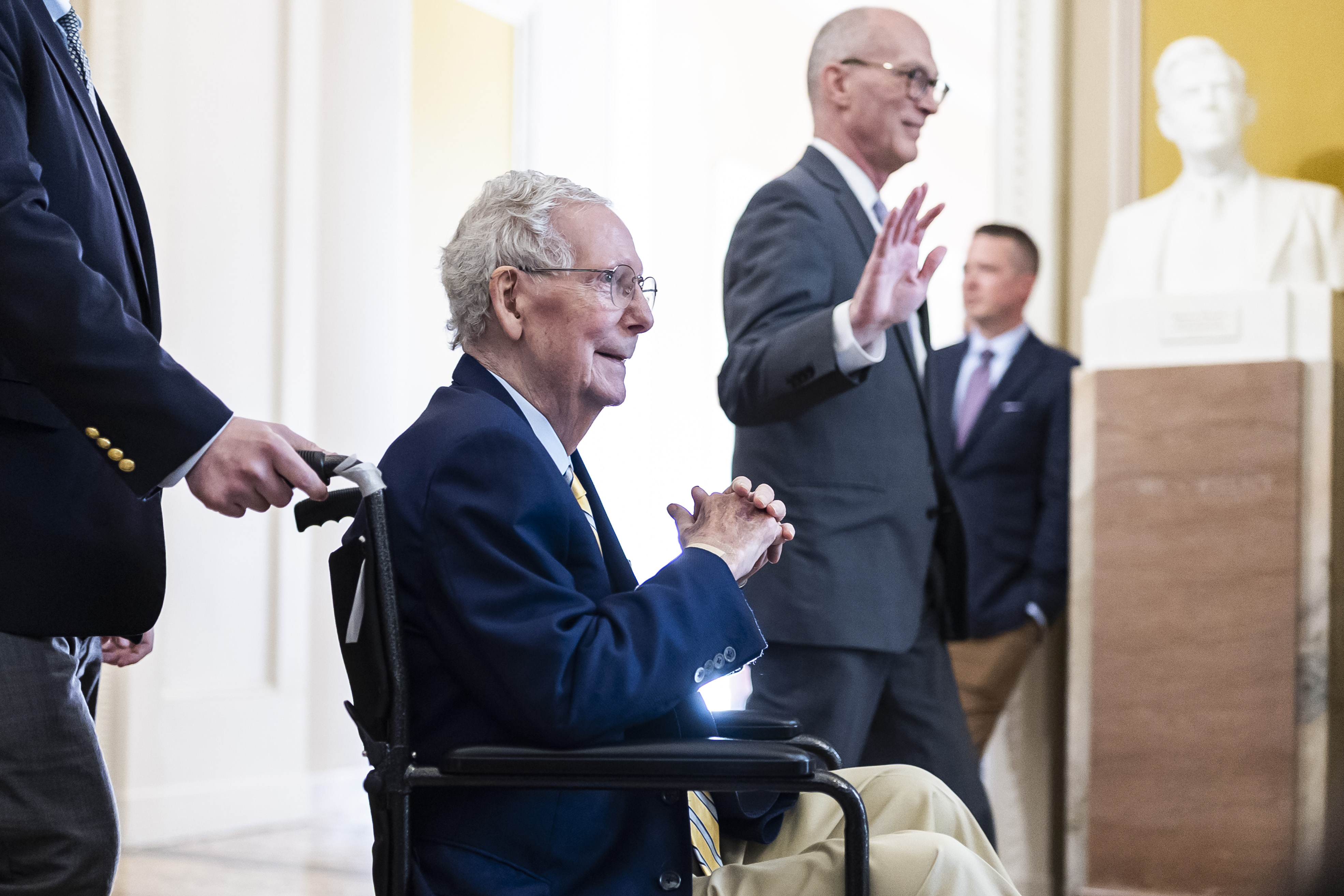 McConnell sits with his hands clasped as an aide pushes his wheelchair through the U.S. Capitol on September 14, 2026. He smiled as he moved through the building for his return to Senate voting. | Source: Getty Images