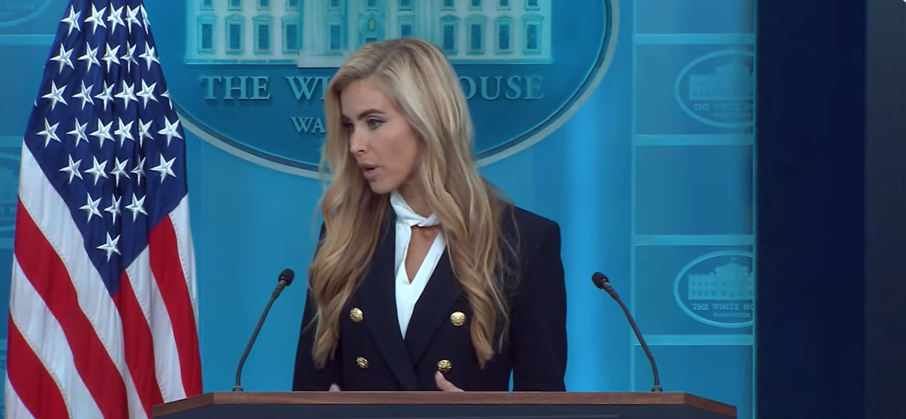 Katie Zacharia speaks at the White House briefing podium while discussing plans to maintain and potentially expand access for new media outlets, praising her predecessor, Karoline Leavitt. | Source: YouTube/The White House