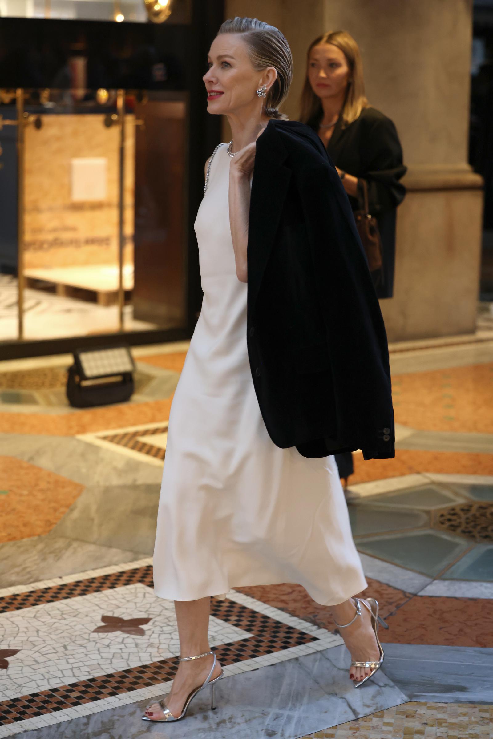 Watts walks through the venue in a white midi dress and silver heels with a black jacket draped over her shoulders. | Source: Getty Images