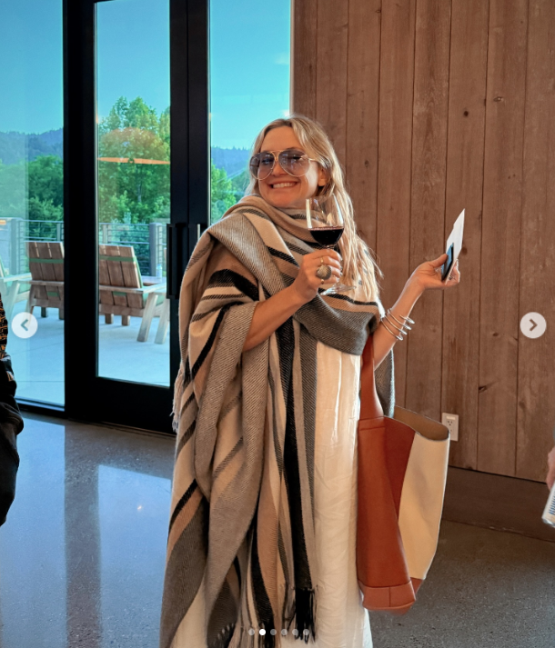 At Kate Hudson's BottleRock Napa weekend, she smiled warmly while wrapped in a cozy striped shawl, holding a glass of red wine and a ticket. With oversized sunglasses and relaxed vibes, she exuded effortless style | Source: Instagram/katehudson