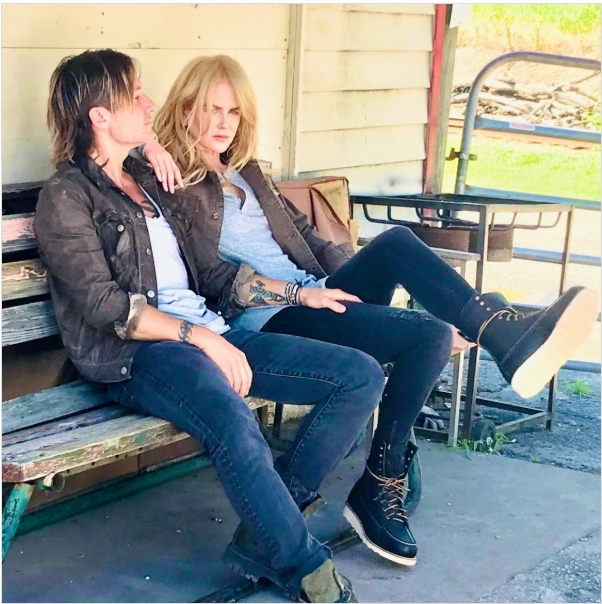 Keith Urban and Nicole Kidman relax on a worn wooden bench outside a sun-bleached farm building, surrounded by rustic touches that reflect the laid-back, lived-in charm of the countryside. From a post dated August 16, 2021. | Source: Instagram/nicolekidman