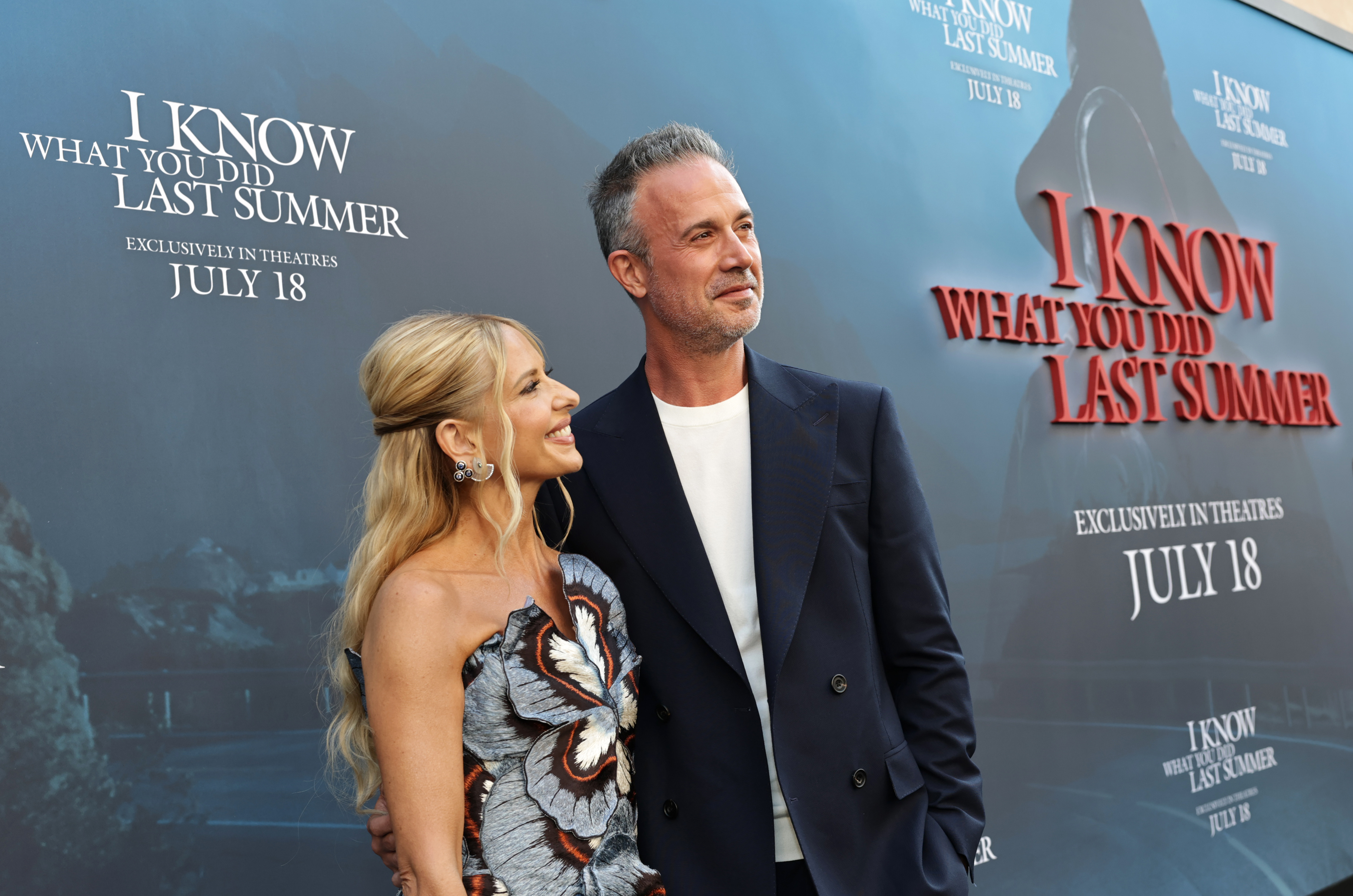 The couple continued posing for the cameras with her looking up and smiling, while he gazes ahead with a soft, content expression. They stand close, with his hand resting behind her back.