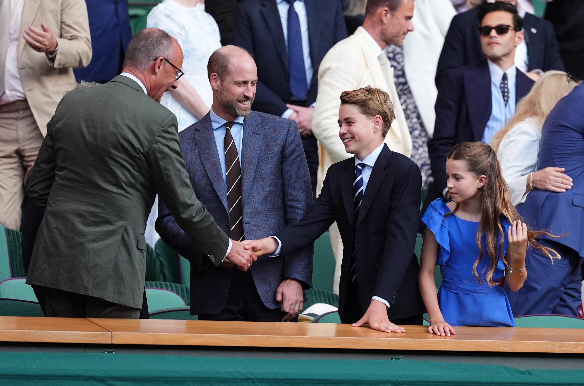 Prince George greeted German Chancellor Friedrich Merz before taking his seat in the Royal Box. The moment highlighted the formal traditions that accompany Wimbledon finals. | Source: Getty Images
