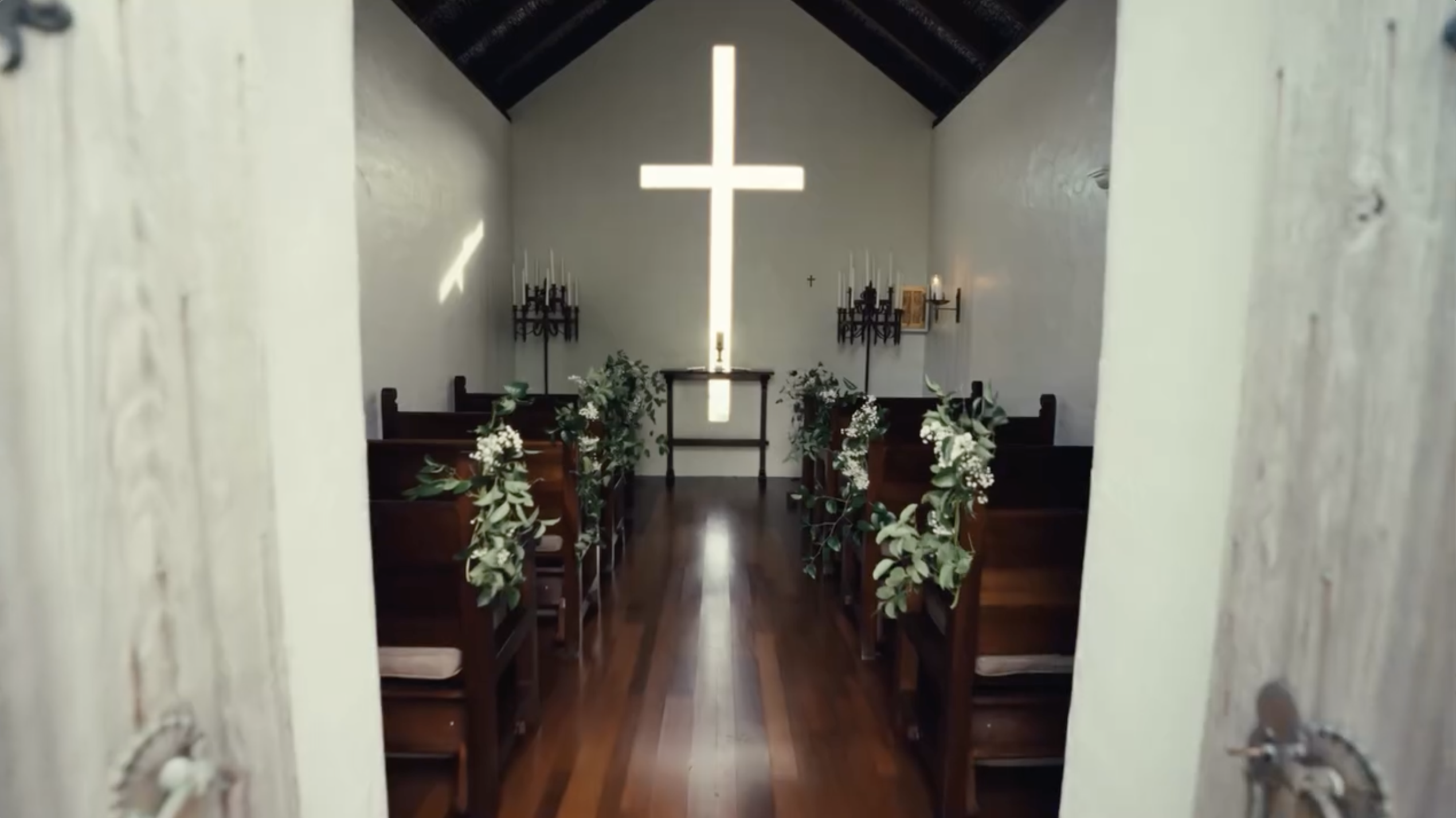 The intimate chapel stands ready for the ceremony, with floral-lined pews leading toward an illuminated cross. | Source: Instagram/donaldjtrumpjr