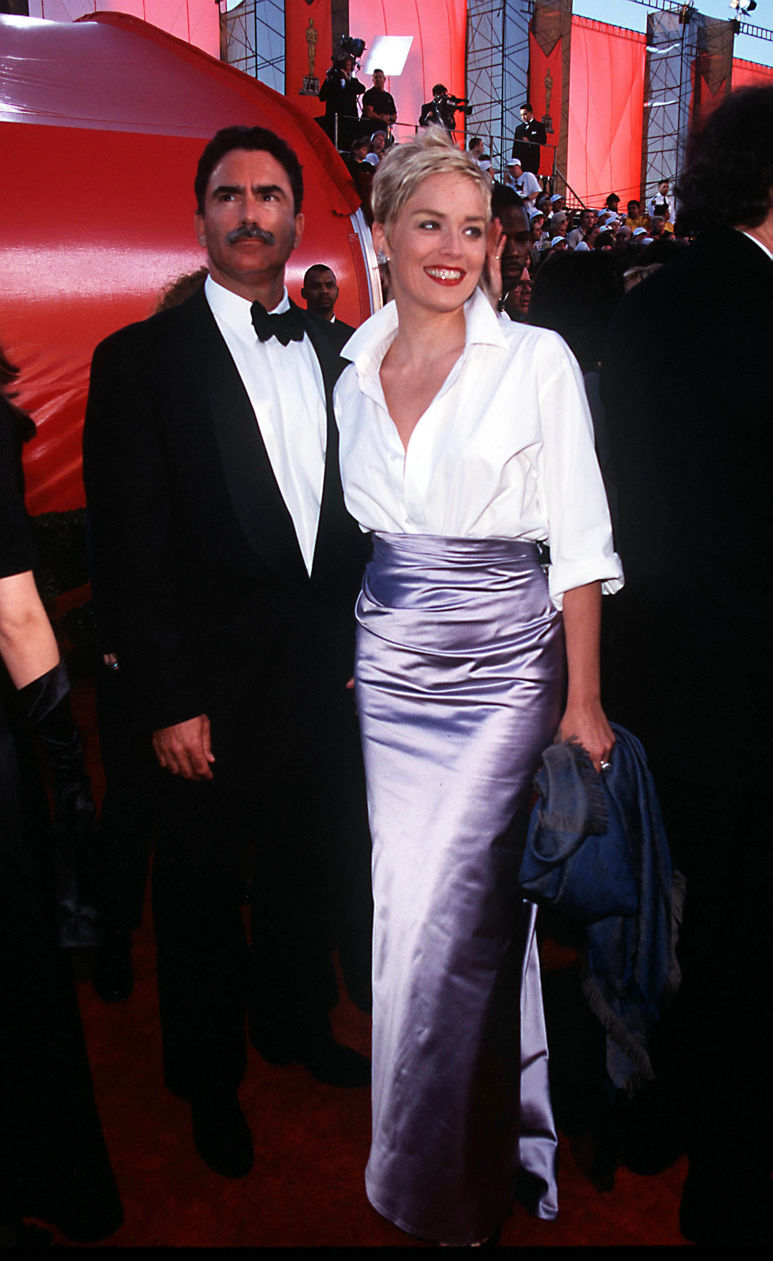 Sharon Stone arrives at the 70th Annual Academy Awards with her then-husband in Los Angeles on March 23. She pairs a crisp white shirt with a lavender satin skirt, smiling brightly on the red carpet.