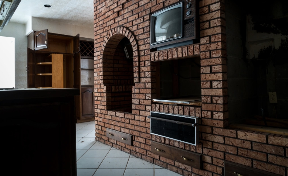 A brick feature wall fitted with an old television, storage compartments, and arched recesses remained inside Mike Tyson's former mansion after the residence had lost much of its original grandeur. Open cabinetry and darkened surfaces reflected the property's neglected condition before its conversion, when rooms designed for the heavyweight champion's private life were awaiting new functions under Living Word Sanctuary Church. | Source: Facebook/Johnny Joo