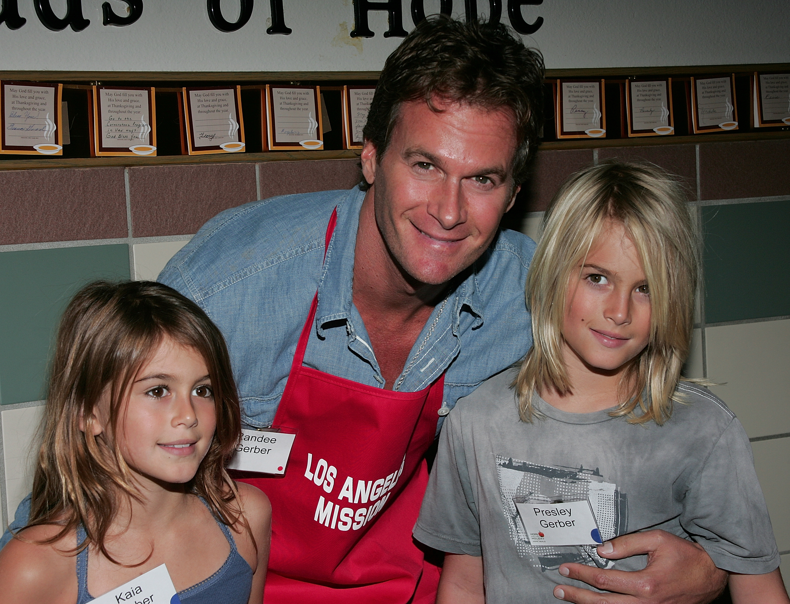 Rande Gerber wrapped his arms around his smiling children, Kaia and Presley Gerber, as the family volunteered together wearing nametags and red aprons at the Los Angeles Mission's Thanksgiving Meal for the Homeless on November 26, 2008, in Los Angeles, California. | Source: Getty Images