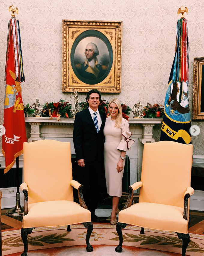 John Wakefield stands in a dark suit with a composed, professional smile, while Pam Bondi, in a fitted neutral-toned dress with a bow detail, smiles warmly beside him. | Source: Instagram/pambondi