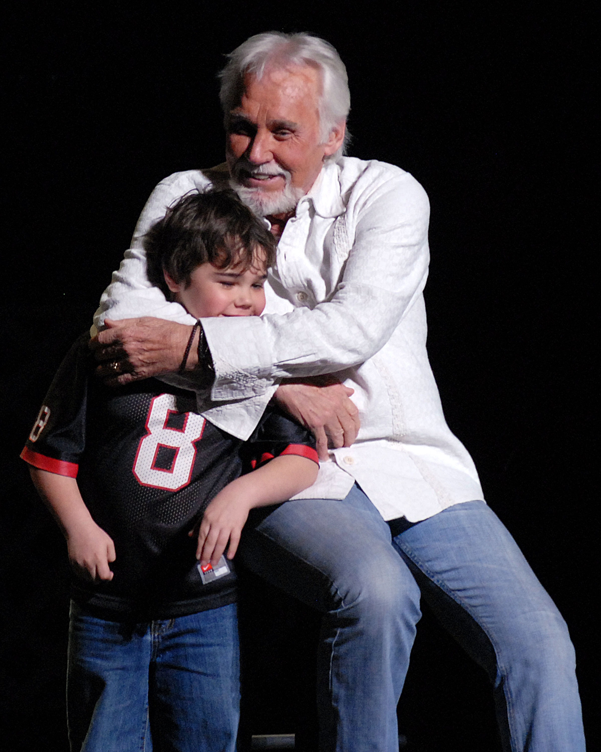 In a tender father-son moment, Kenny Rogers wrapped one of his twin sons in a warm embrace onstage, smiling as the young boy stood close to his famous dad. | Source: Getty Images