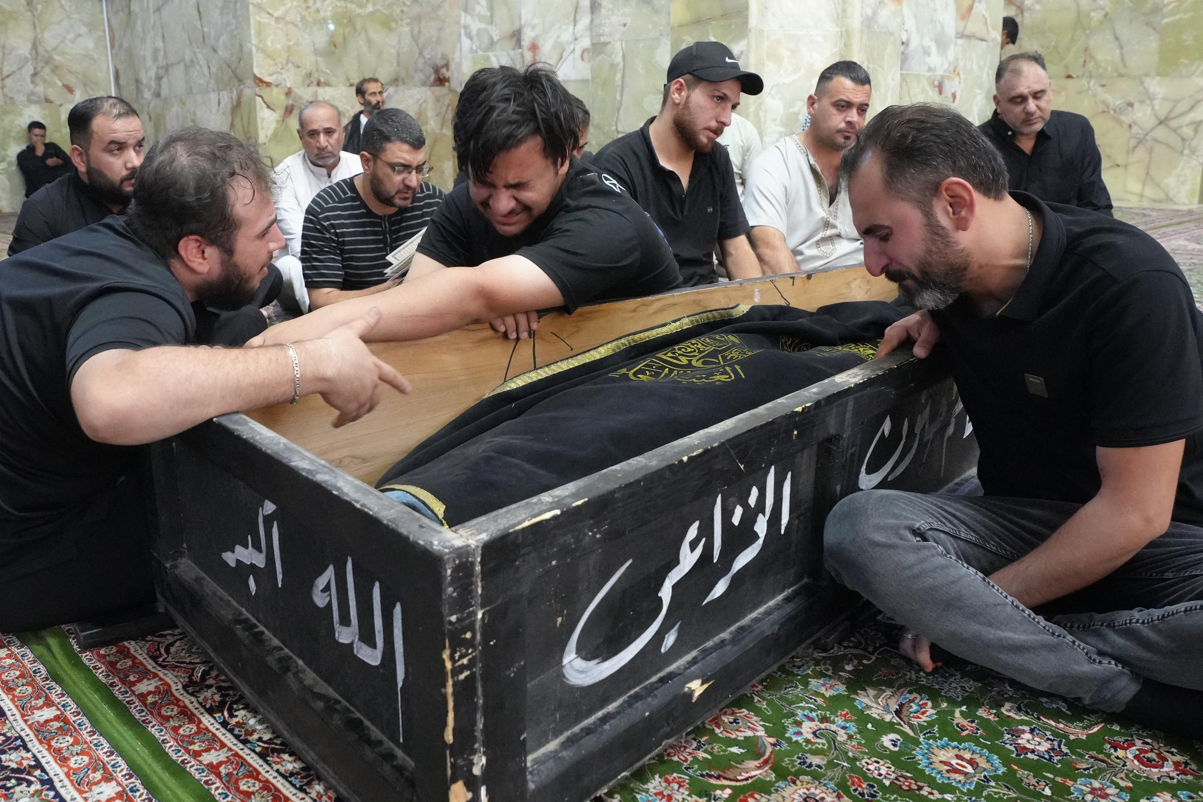 Men mourn over the coffin of a relative that died in the Hyper Mall fire in Kut, Iraq on July 17, 2025. | Source: Getty Images