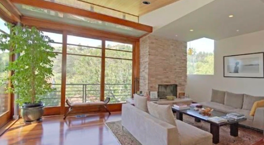 The home's large windows help explain why its living spaces were described as sun-filled. The design brings the surrounding greenery directly into the interior experience. | Source: YouTube/Realtor.com