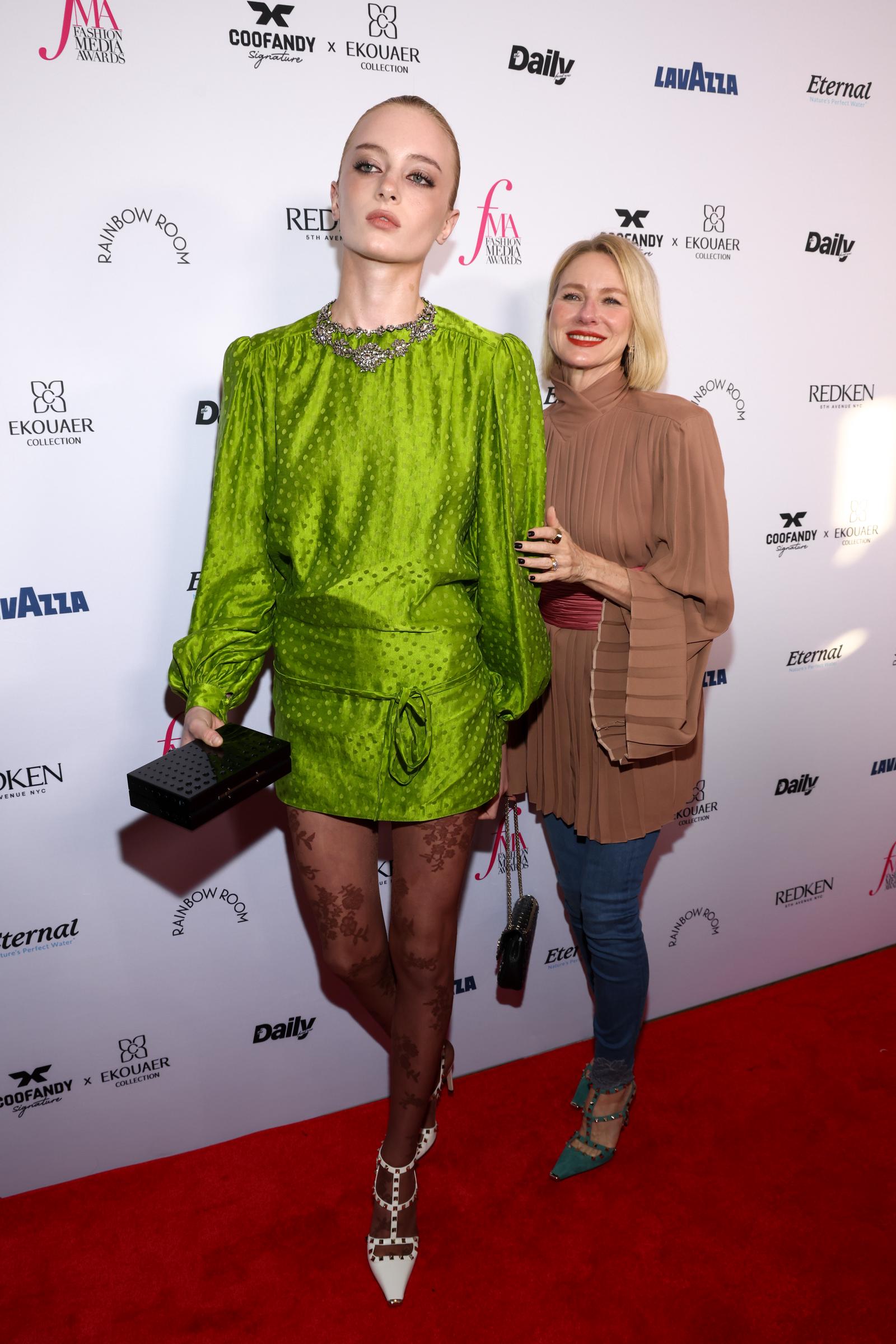 Kai Schreiber and Naomi Watts arrived in style on the red carpet for The Daily Front Row's Fashion Media Awards at the Rainbow Room on September 11, 2026, in New York City. The rising model stood tall in a vivid lime-green Valentino silk mini dress featuring long blouson sleeves, a gathered tie belt, and an ornate crystal collar, styled with floral-patterned tights, a black clutch, and white rockstud pointed-toe pumps. Mother Watts beamed proudly beside her, sporting a pleated taupe high-neck tunic with flared sleeves, fitted denim, and teal studded cage heels. | Source: Getty Images