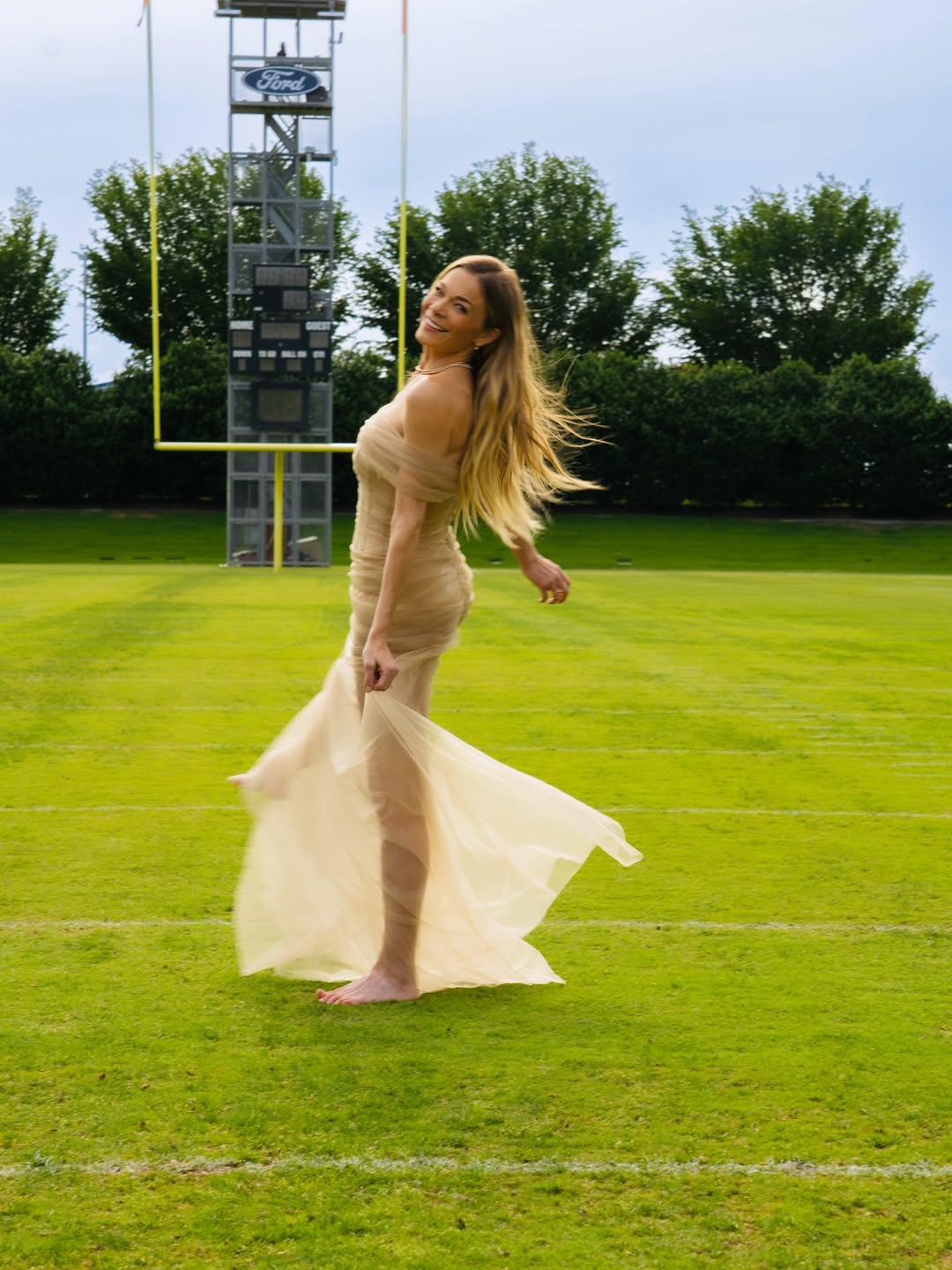 Leann Rimes standing barefoot in a field while holding onto her dress, dated May 9, 2025 | Source: Instagram/leannrimes