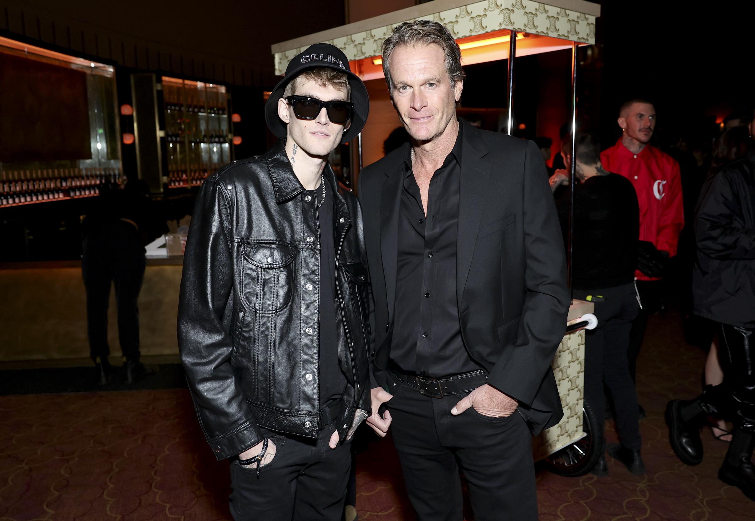 Presley Walker Gerber stood alongside his father, Rande Gerber, at the Celine fashion show at The Wiltern on December 8, 2022, in Los Angeles, California. The father-son pair coordinated in sharp all-black ensembles, with Presley rocking an edgy oversized leather biker jacket paired with dark shades, a Celine bucket hat, and silver chains, while Rande opted for a tailored suit and button-down shirt. | Source: Getty Images