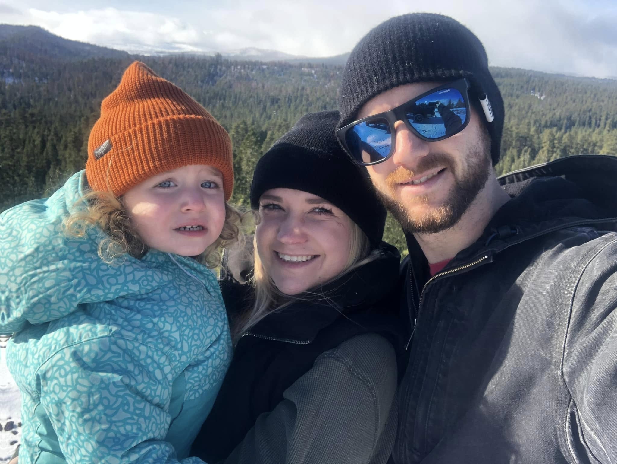 Kaylub Giamanco stands alongside his wife, Kelsey, and their daughter against a scenic mountain backdrop in an outdoor family snapshot. Known for his deep devotion to his children and his local community, Giamanco has spent more than 30 years building his life in Oregon. Family members emphasize that his instinct to protect loved ones has always guided his daily life, long before crisis ever touched the elementary school his young children attend. | Source: Facebook/Kaylub Giamanco