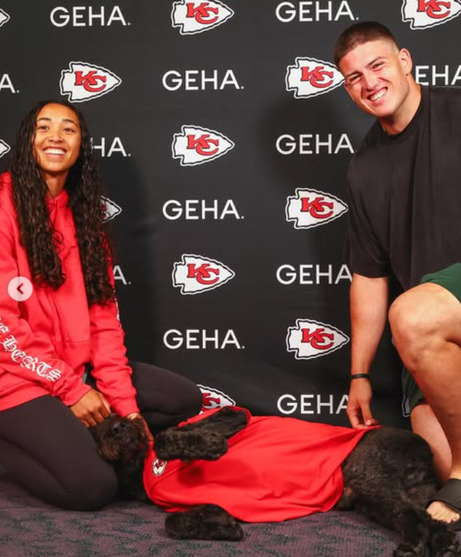 George Karlaftis and Kaia Harris pose beside their black dog during a Kansas City Chiefs-themed event. | Source: Instagram/chiefs and nfl
