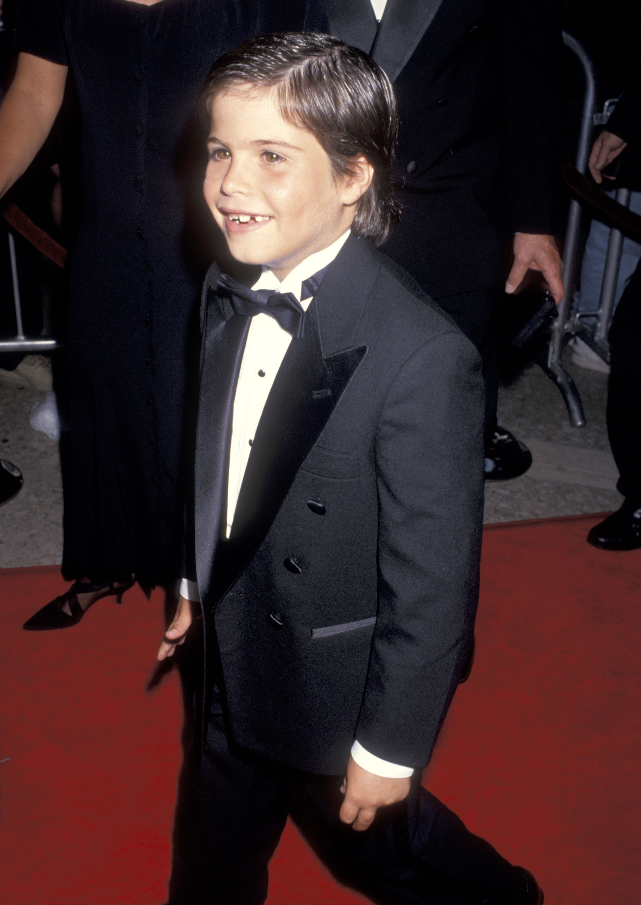 The young actor smiles in a black tuxedo and bow tie at the Sleepless in Seattle premiere on June 23, 1993 — just days before the film opened nationwide and changed his childhood career.