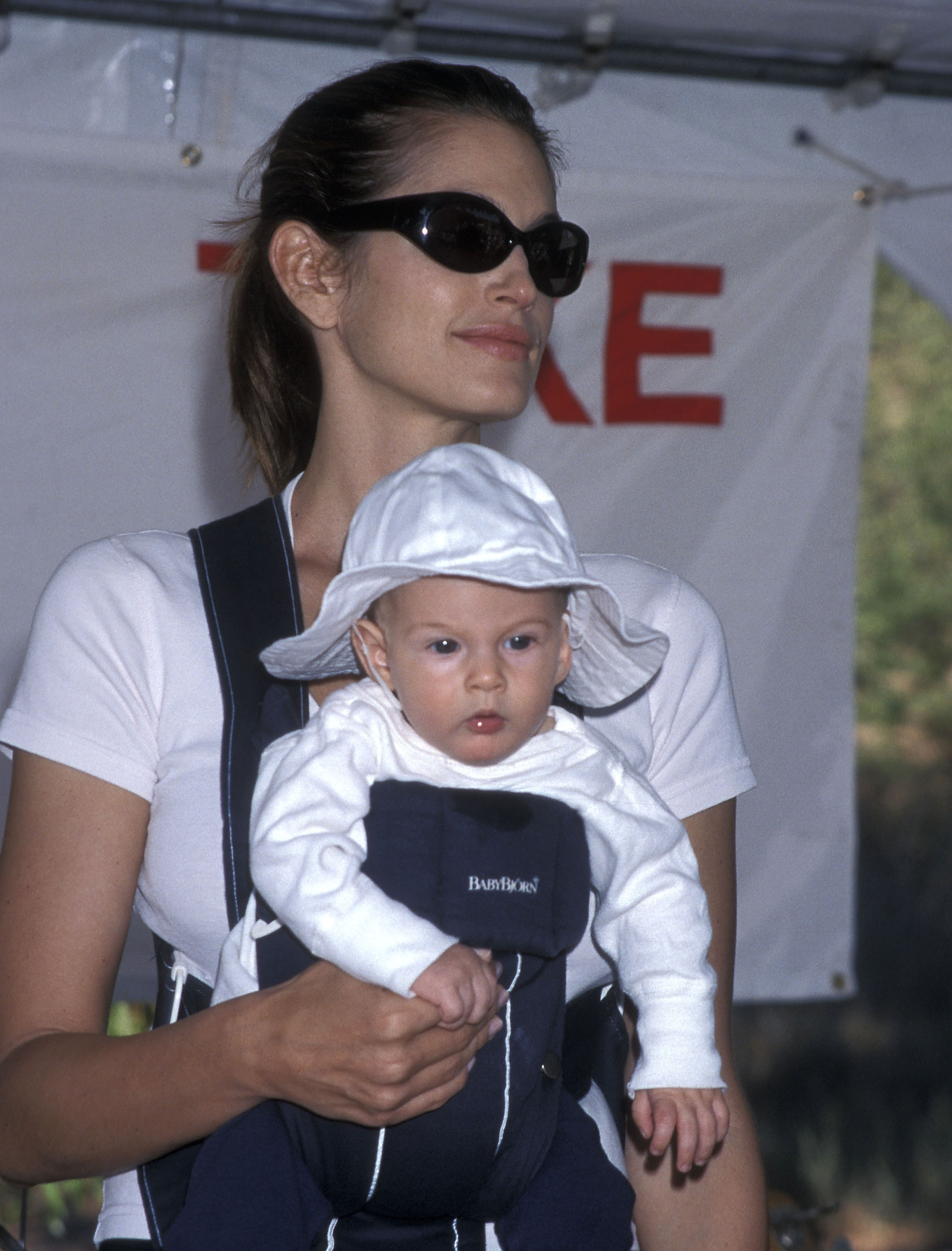 Supermodel Cindy Crawford carried her infant son, Presley Gerber, in a front baby carrier while attending a charity run for breast cancer research at Paramount Ranch in Agoura Hills, California, on October 9, 1999, keeping cool under dark sunglasses as her baby sported a white bucket hat. | Source: Getty Images