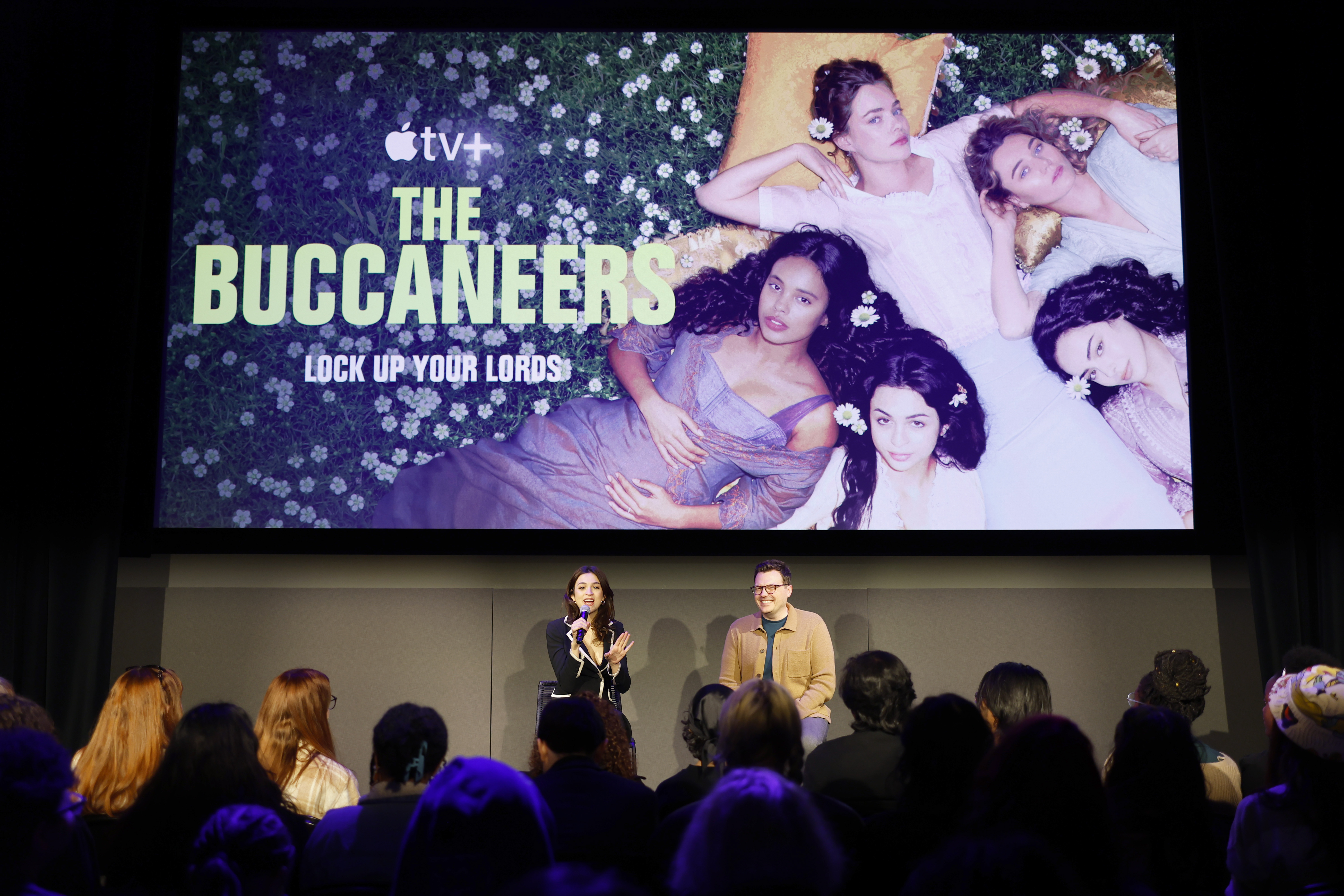 Josie Totah speaks during The Buccaneers panel on the second day of the 12th SCAD TVfest, seated onstage beside a fellow panelist as they address an audience. A large promotional image for the Apple TV+ series appears on the screen behind them. | Source: Getty Images