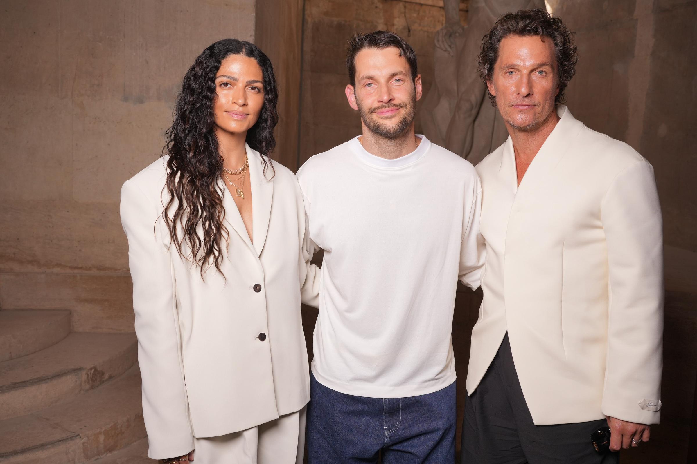 At the event, Alves and McConaughey pose with fashion show host Simon Porte Jacquemus, standing on either side of him. The trio shares a warm moment, with Alves and McConaughey's hands gently resting on Simon’s back, drawing them closer together. The image captures a sense of camaraderie and support.