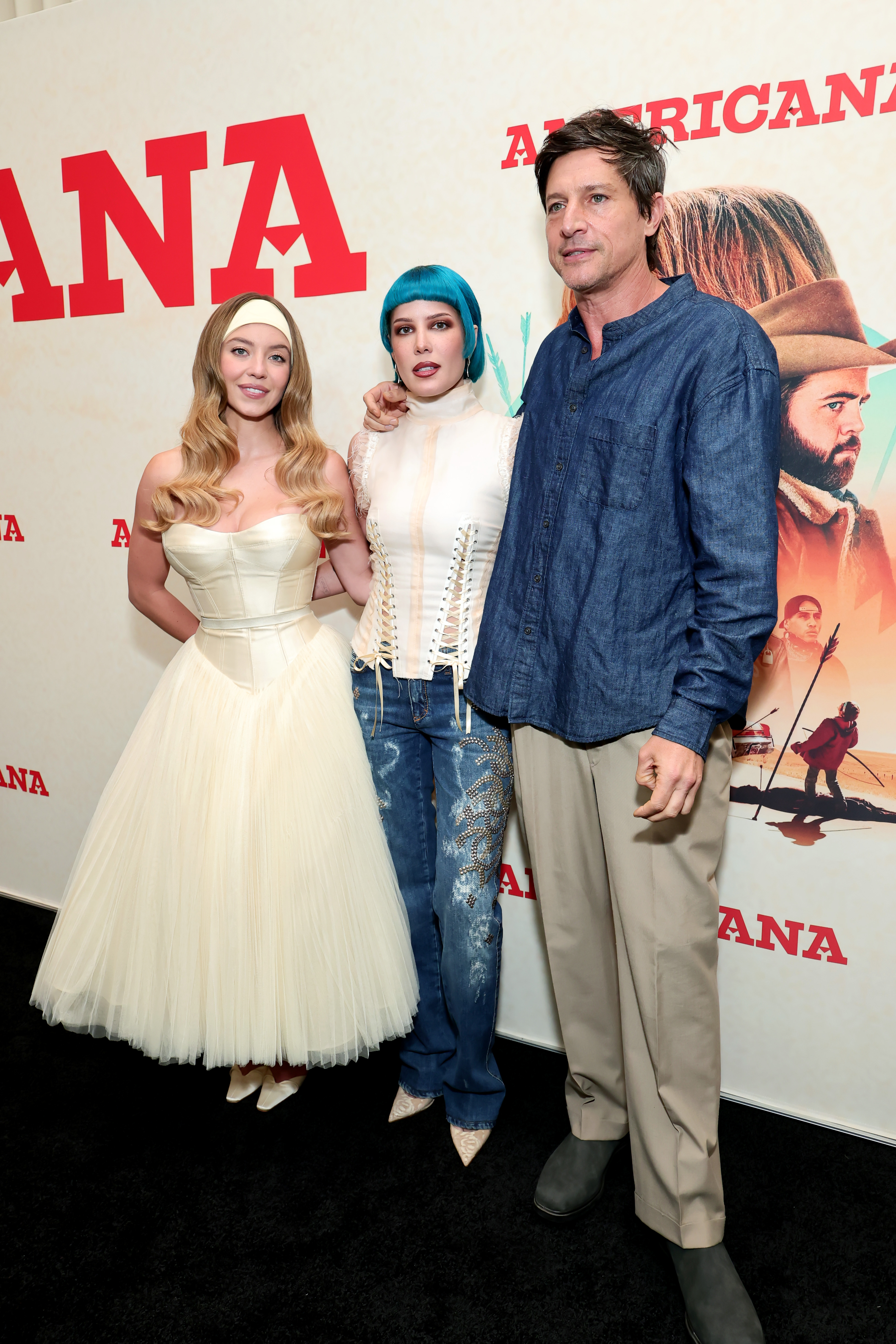 In this group shot, Sydney Sweeney stands with Halsey and Simon Rex, the trio posing together at the event. Sweeney’s ivory gown brings a classic contrast to Halsey’s bold style and Rex’s laid-back look, with her headband adding a distinct finishing touch.