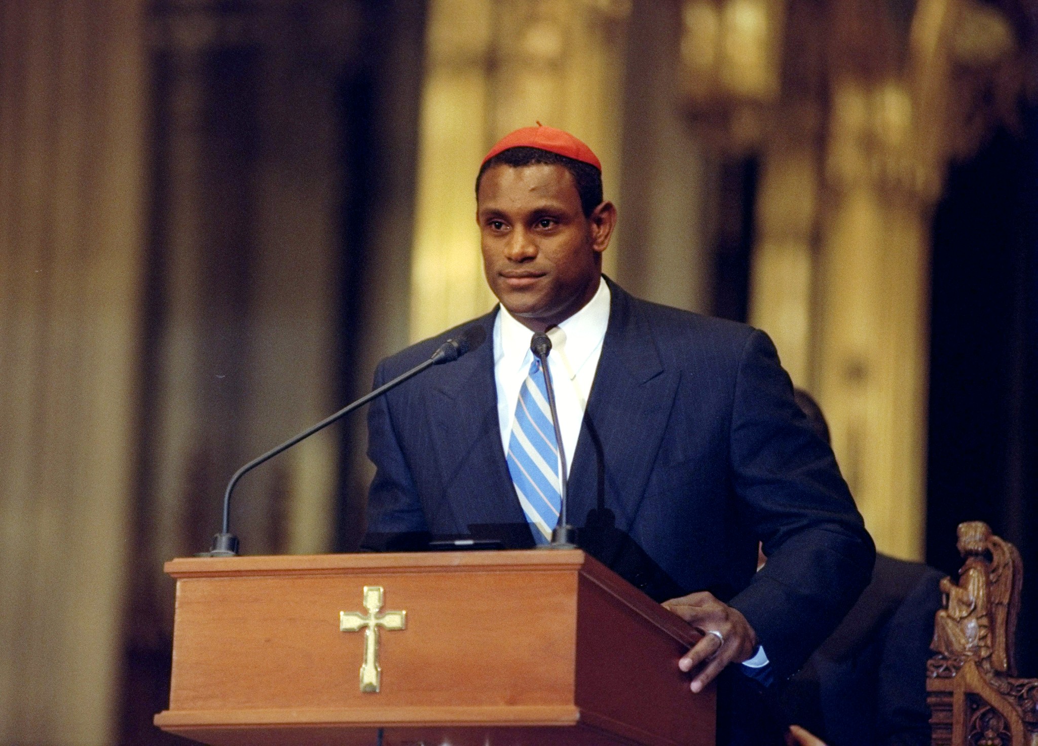 Sammy Sosa stood at a lectern inside St. Patrick's Cathedral in New York City, where the Chicago Cubs star was honored on October 16, 1998. Wearing a dark suit and striped tie, Sosa addressed the gathering after a remarkable season in which he hit 66 home runs and became one of baseball's most prominent figures during his memorable pursuit of the single-season home-run record alongside Mark McGwire.