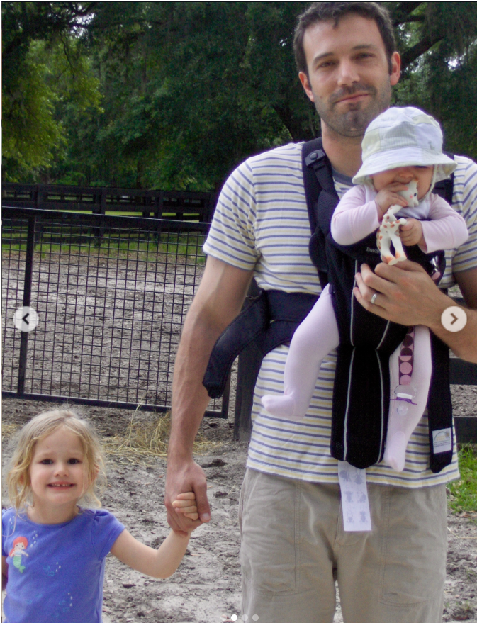 Ben Affleck walks hand in hand with one daughter while carrying another in a baby carrier during a visit to what appears to be an animal enclosure. The candid throwback photo was one of two images Jennifer Garner included in her Father's Day tribute that quietly honored the father of her three children. | Source: Instagram/jennifer.garner