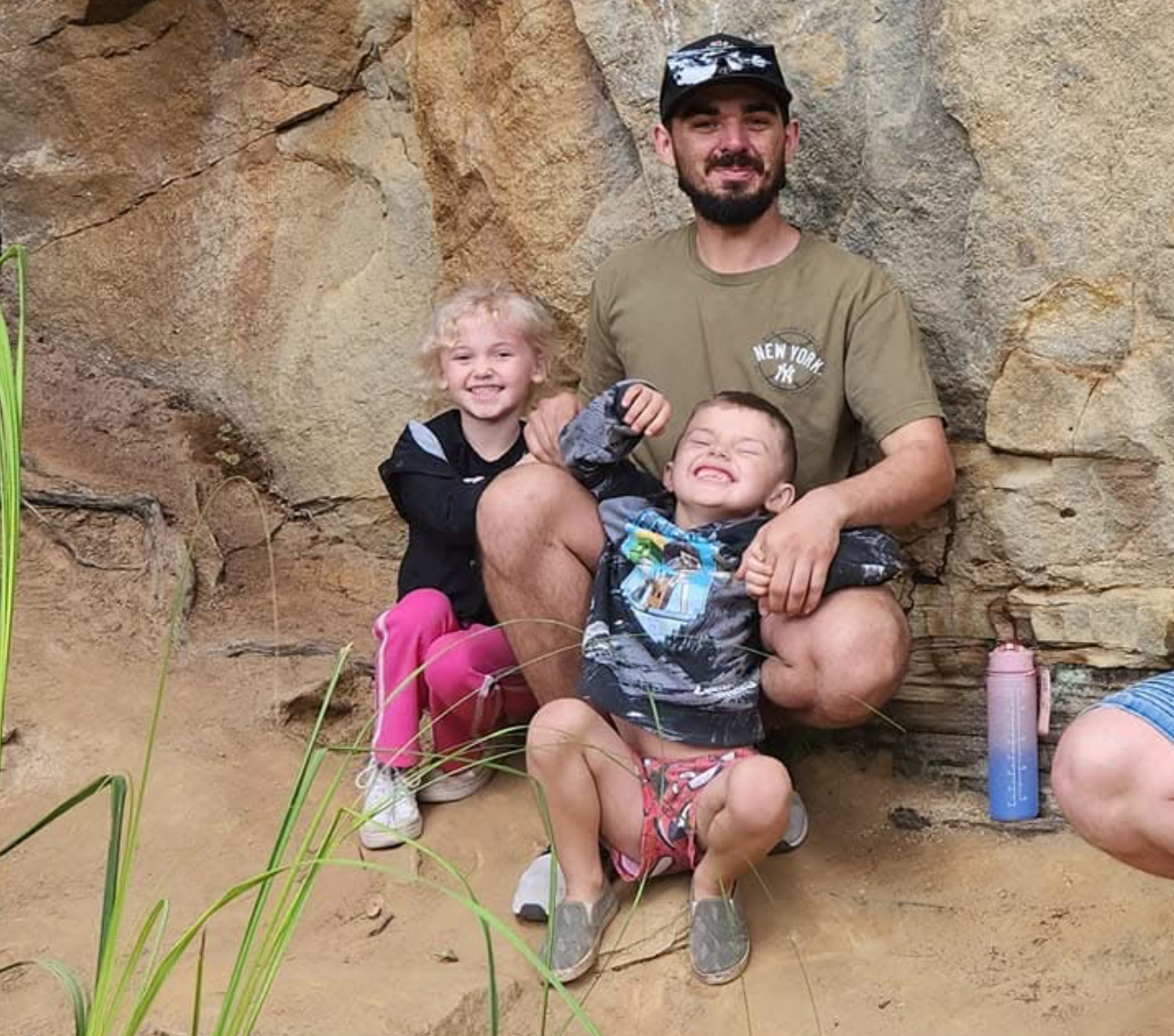 Shaun Ranger with his children Baylee and Chandler smiling and leaning on a rock outcropping in an undated picture. | Source: GoFundMe