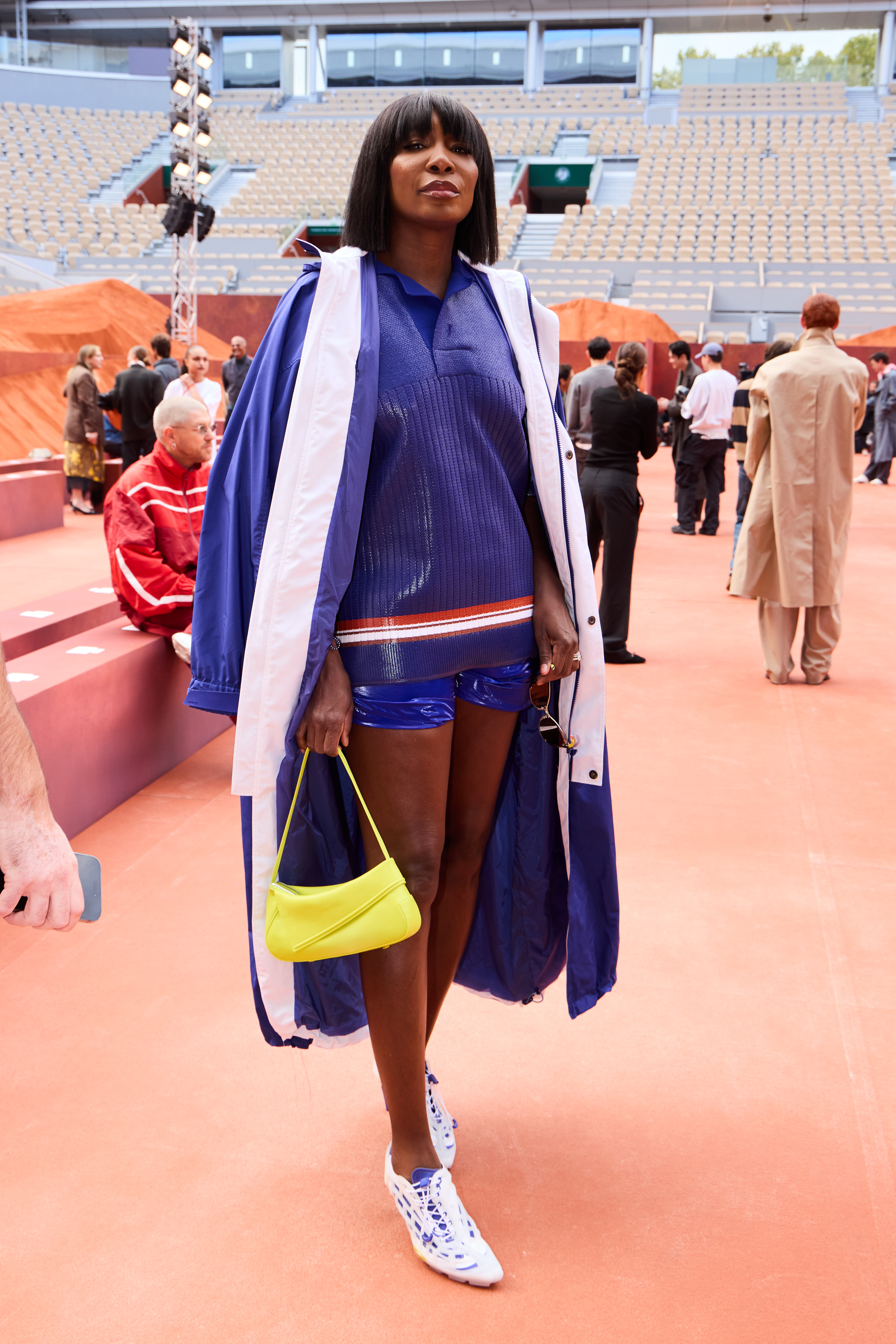 Venus Williams brings tennis-inspired dressing to the front row in blue, white, and a flash of bright yellow. Her Lacoste appearance blends the sporty pieces she is known for with a Fashion Week finish.