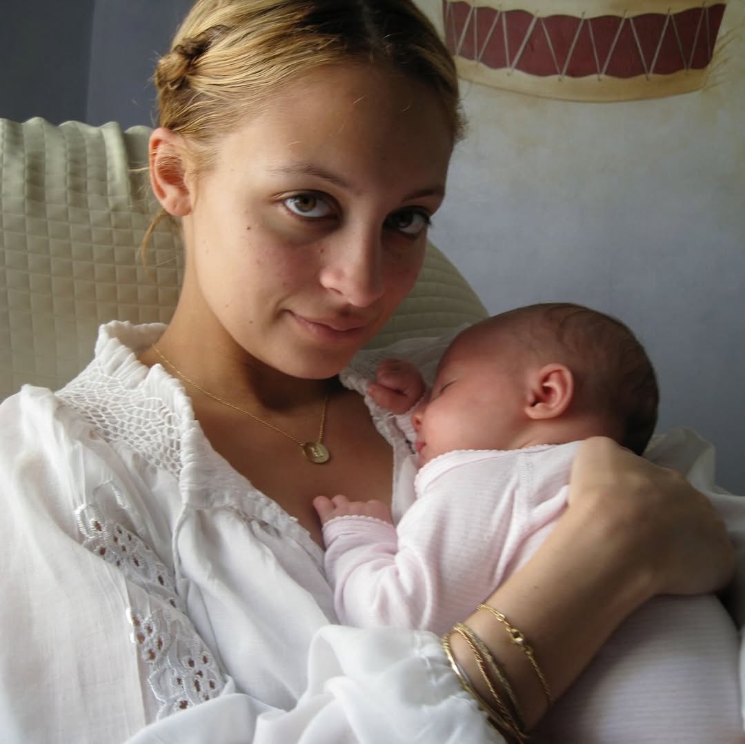 Nicole Richie cradles baby Harlow Winter Kate Madden against her chest in a quiet close-up portrait. Dressed in soft white and pink tones, mother and daughter share a tender early moment as Kate rests peacefully in her mother's arms. | Source: Instagram/nicolerichie and joelmadden