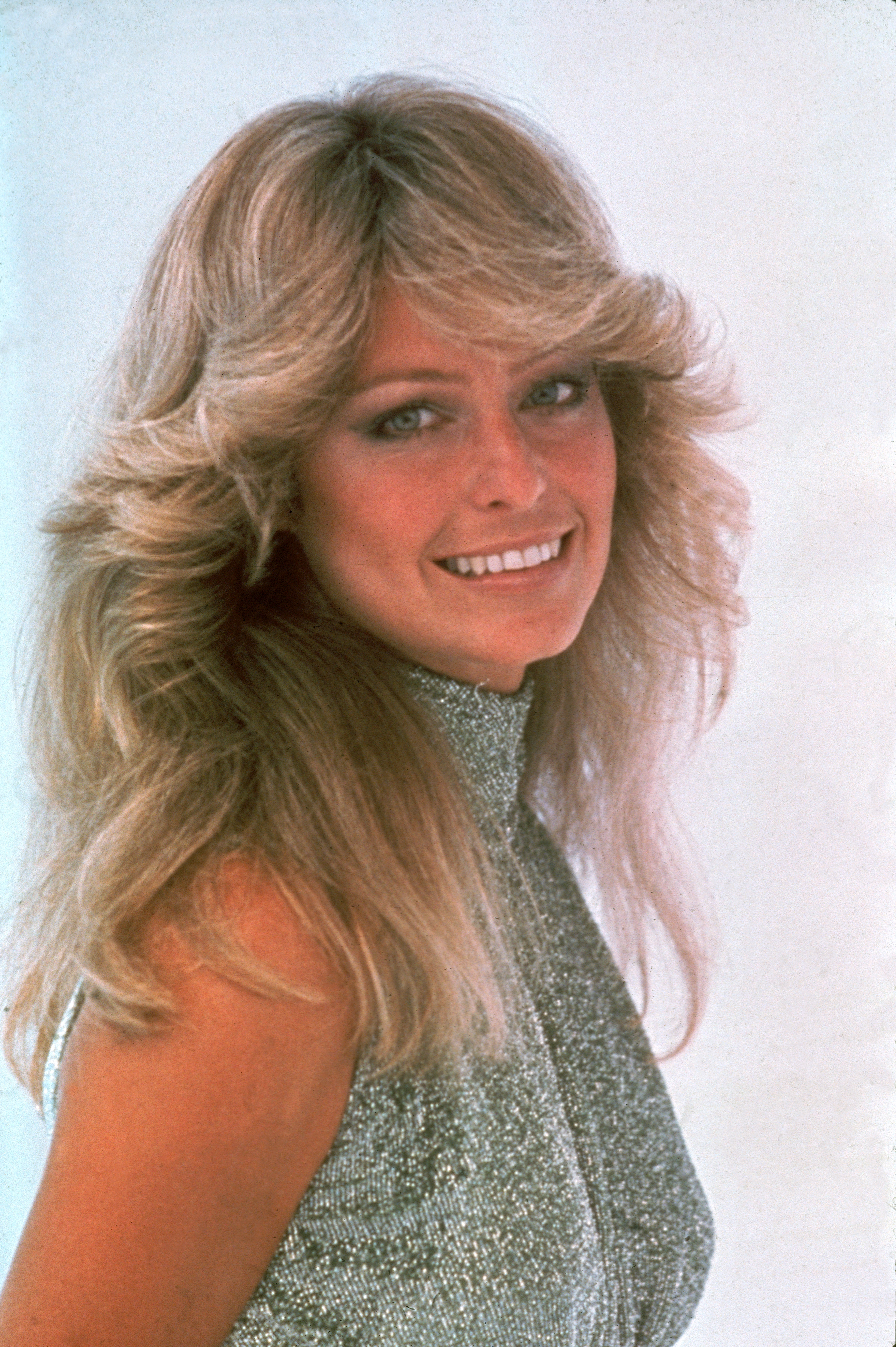 Portrait of late actress Farrah Fawcett, dressed in a high-necked, sleeveless outfit, June 1977. | Source: Getty Images