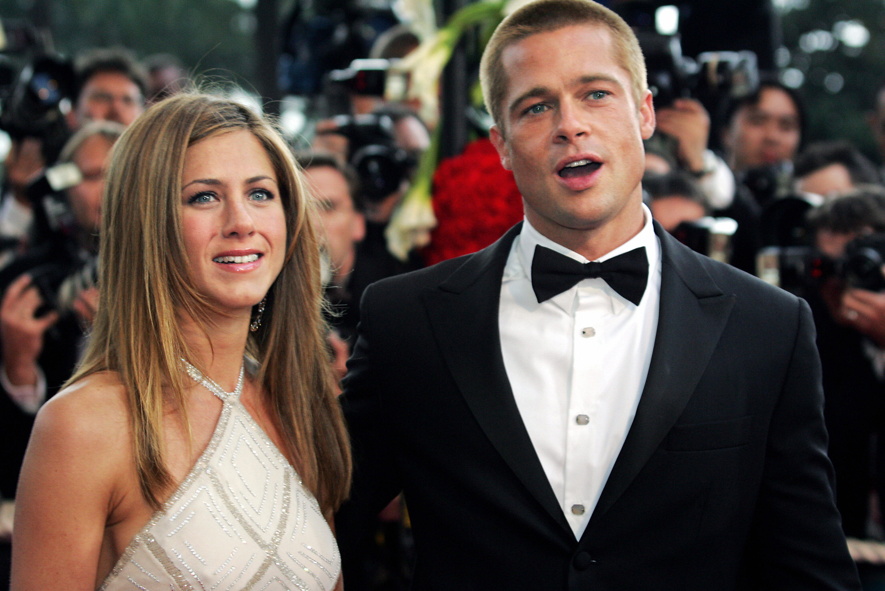 Jennifer Aniston and Brad Pitt appear amid flashing cameras, bright festival lights, and crowded photographers during their high-profile arrival at the Cannes Film Festival.