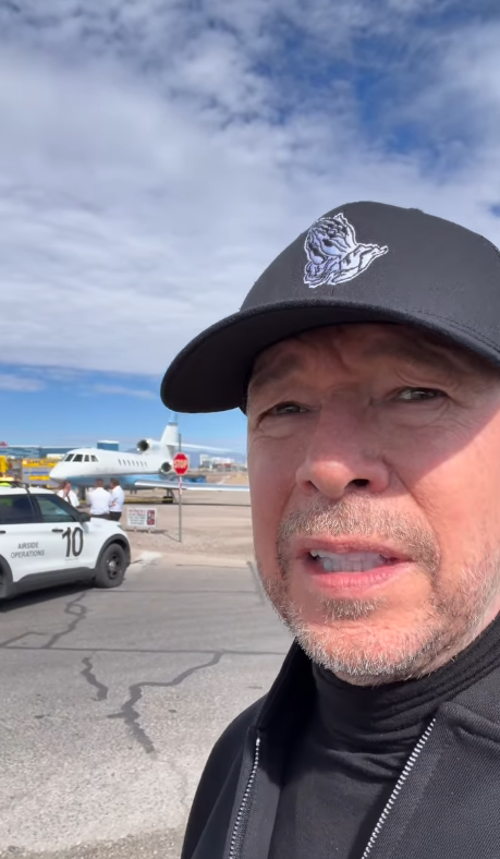 Donnie Wahlberg records a video near Harry Reid International Airport in Las Vegas after his private jet's aborted takeoff on October 18, 2026. An aircraft and an airport operations vehicle are visible behind him as he addresses concerns about the incident. | Source: Instagram/donniewahlberg
