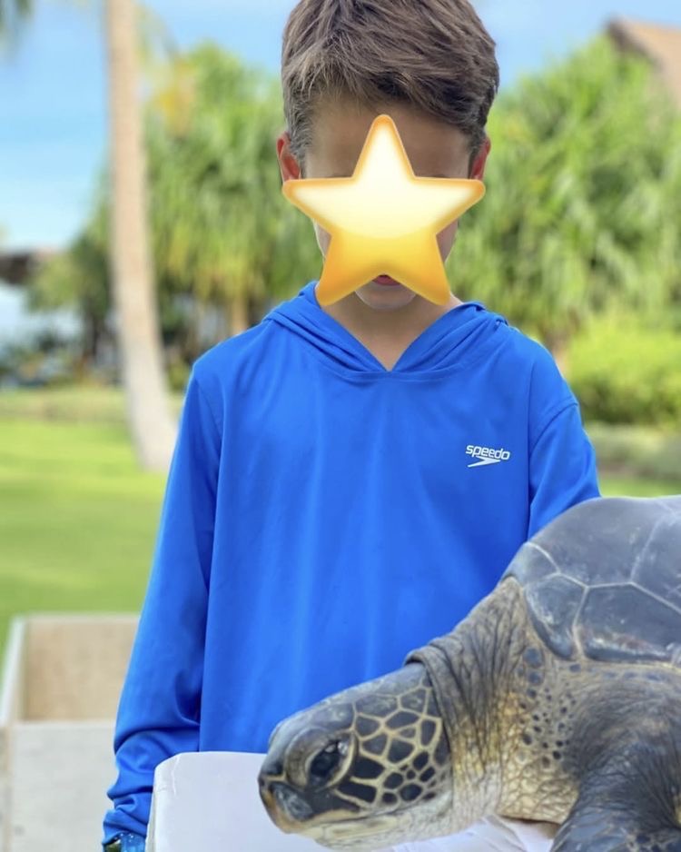 Rocky Prinze posed beside a giant tortoise during a family outing, wearing a blue hoodie with his face covered by a star emoji. His parents continued protecting his identity in childhood photographs, years before he began sharing his passion for racing. | Source: Instagram/@sarahmgellar