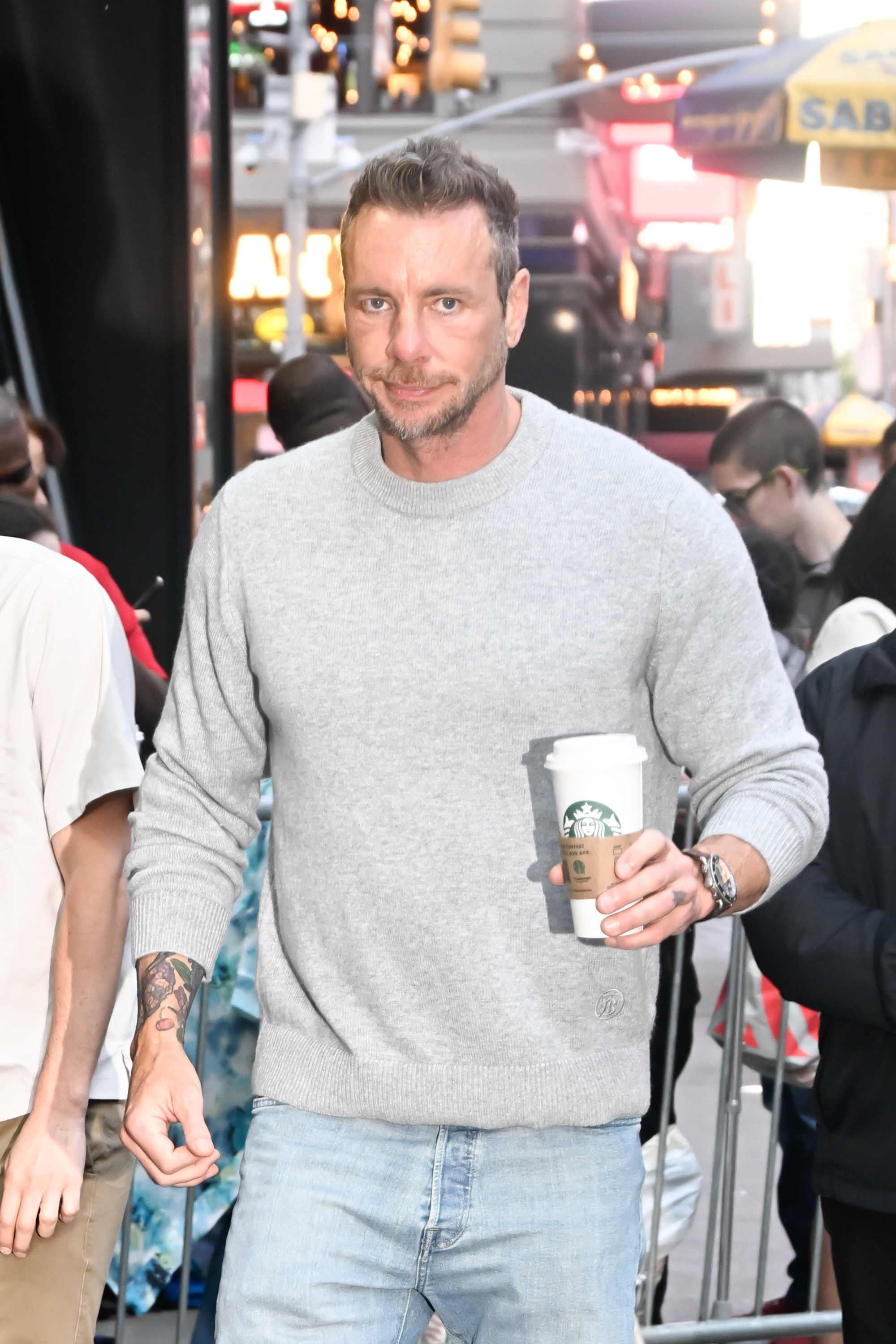 Dax Shepard is seen walking through Midtown Manhattan, dressed in a gray sweater and light jeans with coffee in hand. His focused expression and steady pace cut through the city's morning rush.