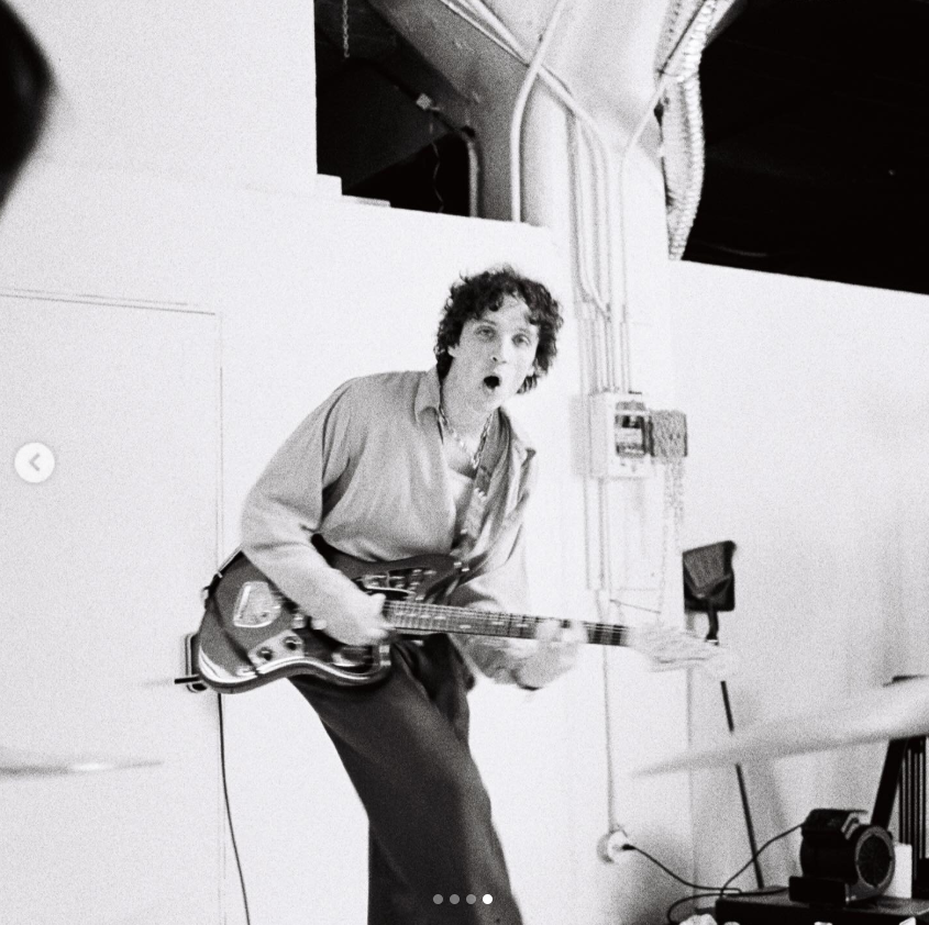 Justin Acee performs with his guitar in a black-and-white photo. The musician has said he wants his songs to become attached to listeners’ memories, drawing inspiration from artists including Andy Shauf, Big Thief, King Krule and The Beatles. He also worked with director David Hinsch on the Ugly Truth music video, with Tallulah joining the creative process | Source: Instagram/justinacee
