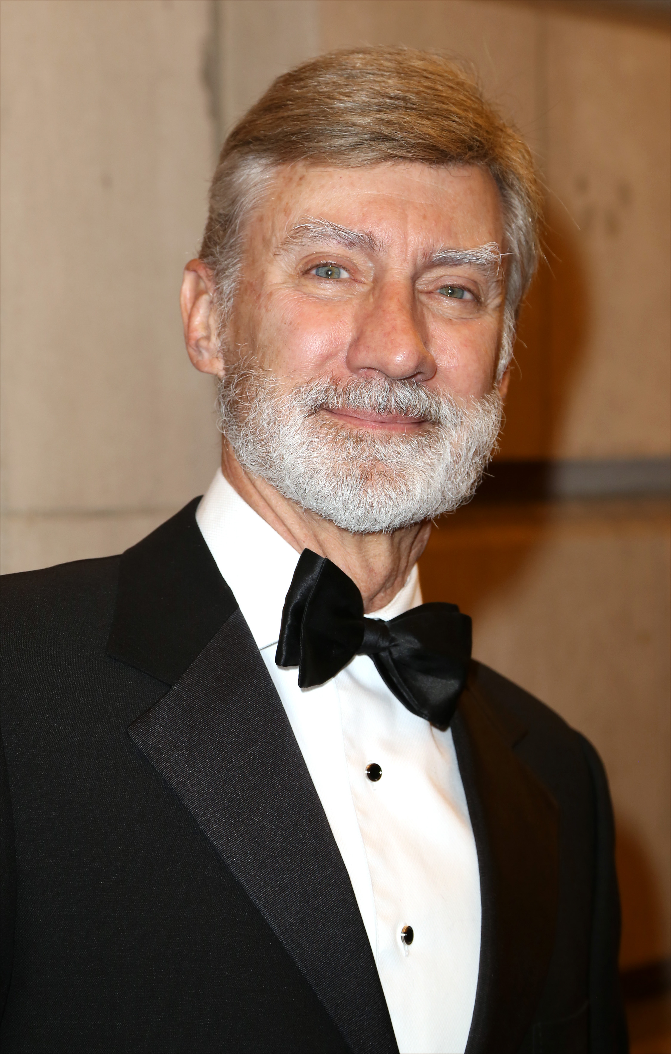 David Garrison looked dashing as he attended the Broadway opening night after-party photo call for "The Visit" at the Lyceum Theatre on April 23, 2015, in New York City. The actor smiled handsomely while sporting a neatly groomed silver-white beard and mustache, dressed to the nines in a classic black tuxedo, crisp white formal shirt, and black satin bow tie. | Source: Getty Images