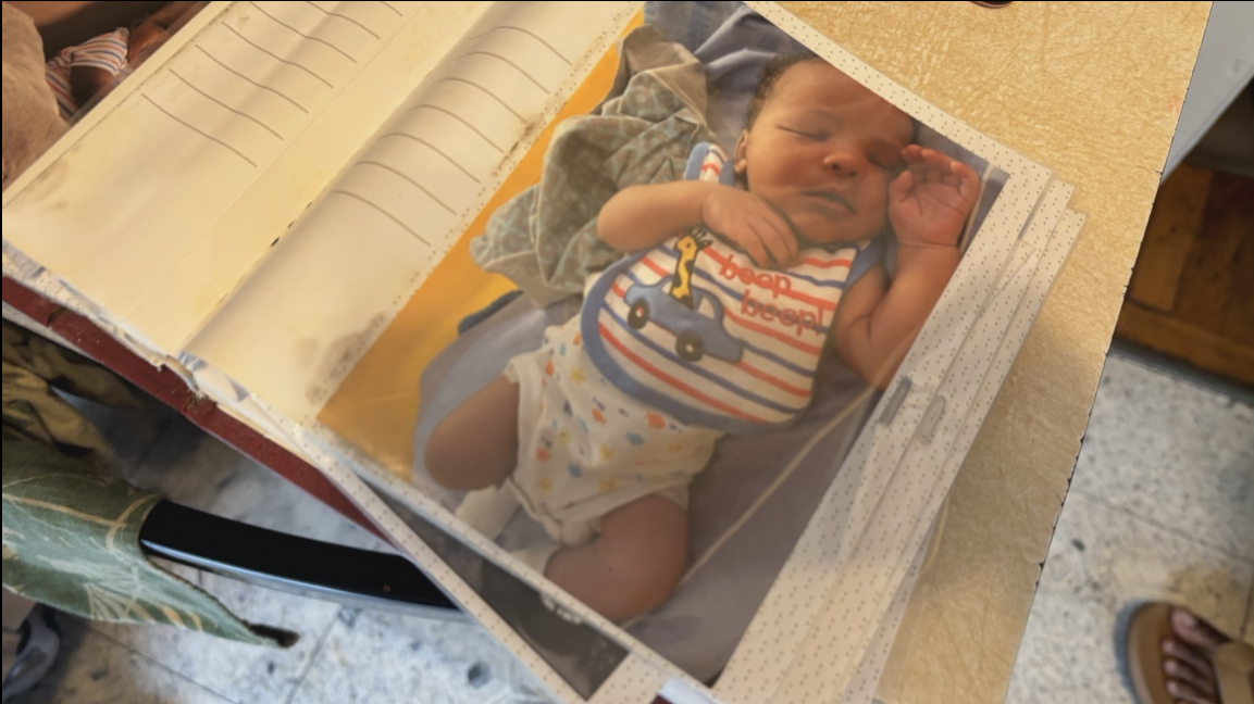 A baby photo of Tadens Joseph resting peacefully in a striped outfit is displayed inside a family photo album. | Source: Facebook/KCTV5 News Kansas City