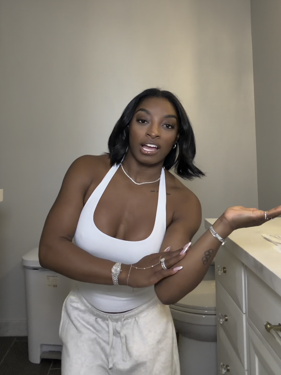 With one arm extended and the other crossed, Simone Biles emphasizes her point mid-explanation, blending vulnerability with poise as her Olympic rings tattoo subtly peeks through. | Source: TikTok/simonebilesowens