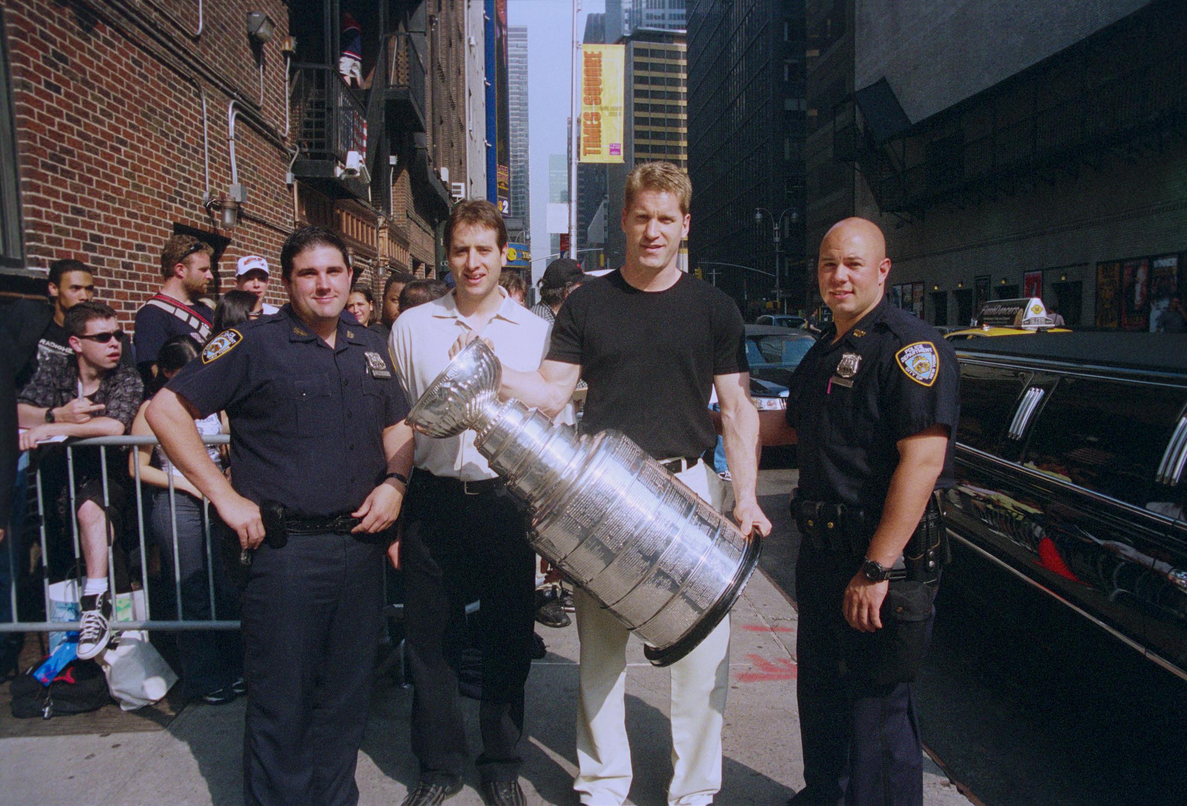 Conn Smythe Trophy winner Claude Lemieux is pictured left of the teammate holding the 1995 Stanley Cup championship. | Source: Getty Images