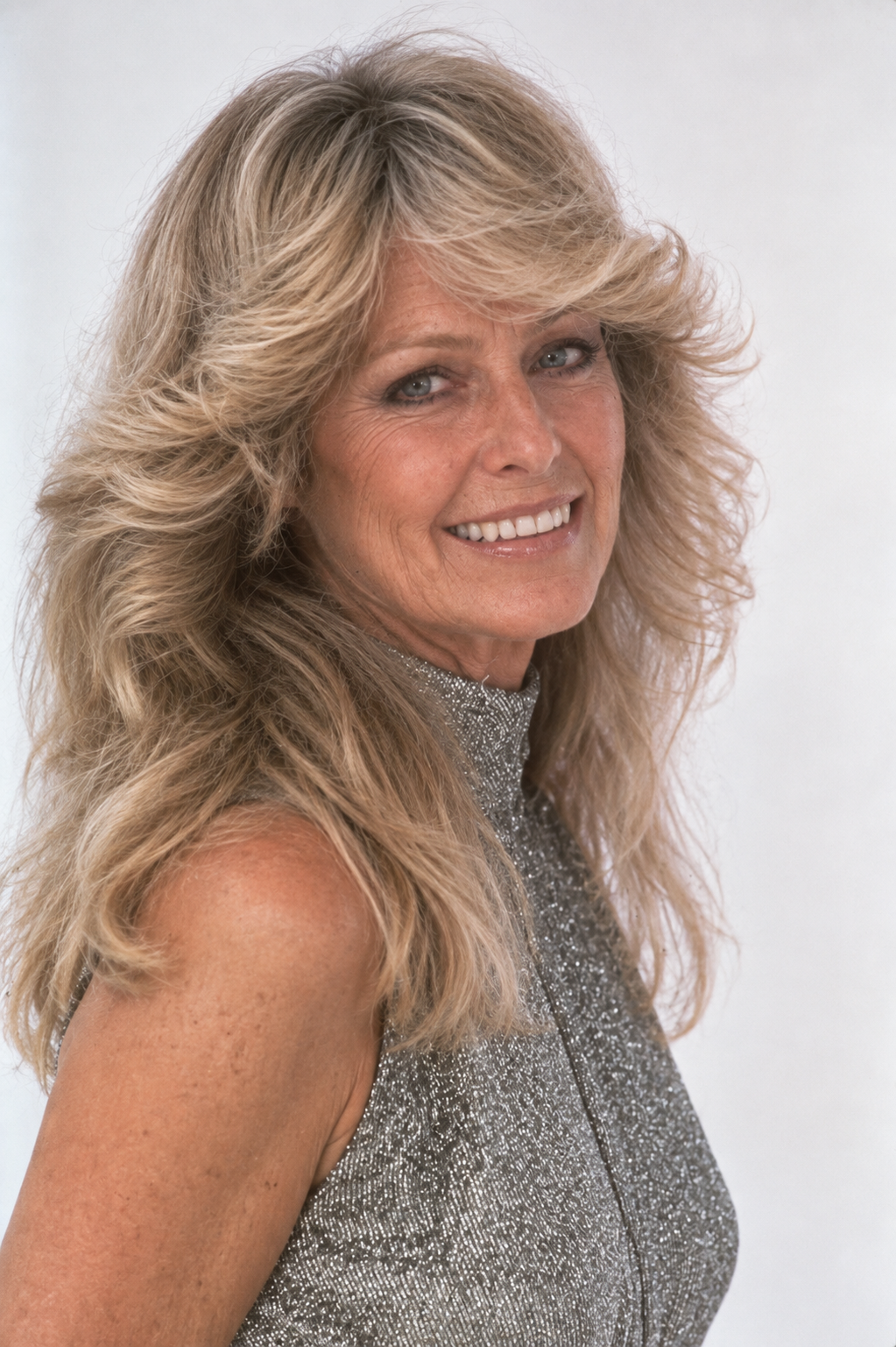 Publicity portrait of Farrah Fawcett smiling while sitting outdoors in blue jeans and a mauve blouse, taken in 1975. | Source: Getty Images