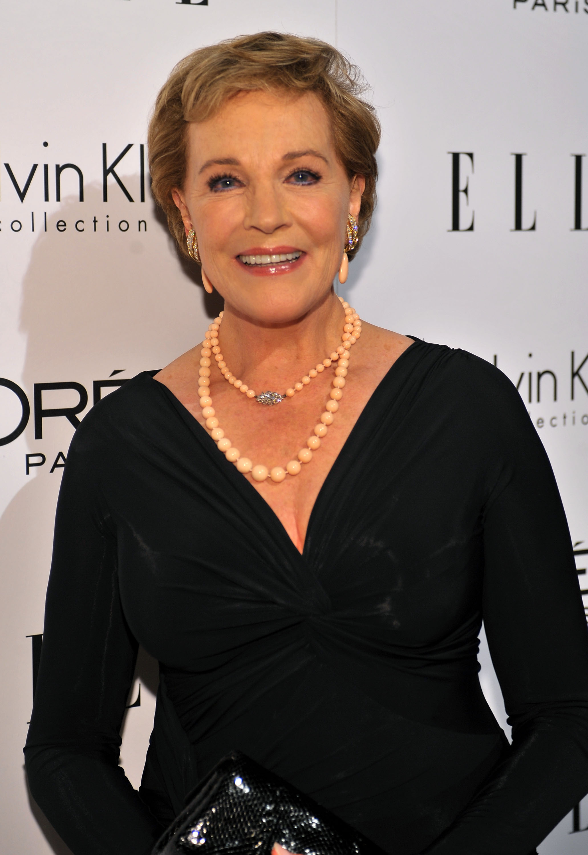 Julie Andrews arrives in style at the 16th Annual ELLE Women in Hollywood Tribute at the Four Seasons Hotel in Beverly Hills, California, on October 19, 2009, where she was honored with the L'Oréal Paris Legend Award. The actress dazzles in an elegant long-sleeved black V-neck gown, paired with a layered double-strand peach beaded necklace featuring a sparkling diamond centerpiece clasp, matching drop earrings, and a glossy black clutch.