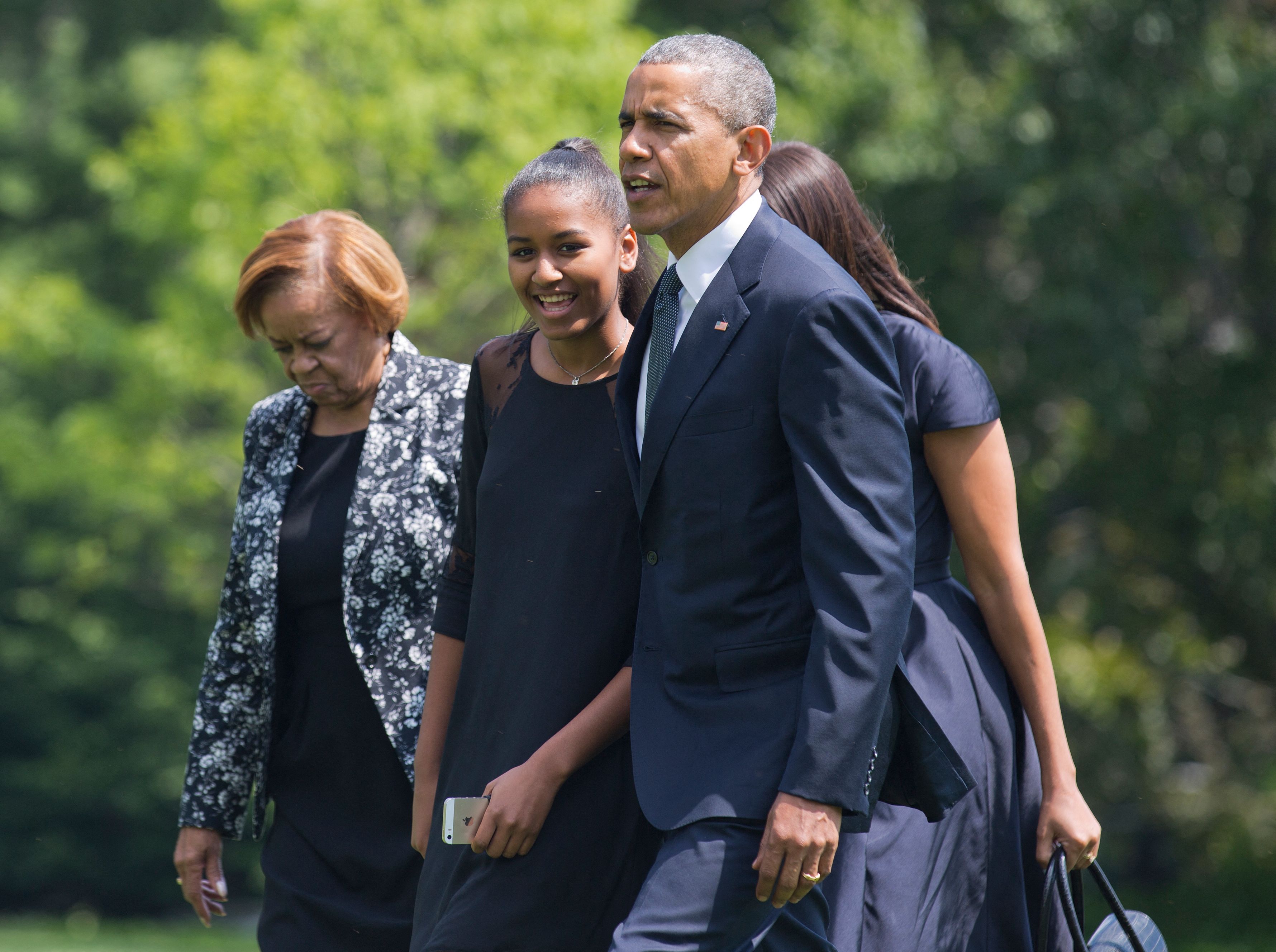 On June 6, 2015, in Washington, D.C., Sasha Obama, dressed in a black outfit and holding her phone, walked alongside President Barack Obama and her grandmother, Marian Robinson, as the family returned from Beau Biden's funeral service.