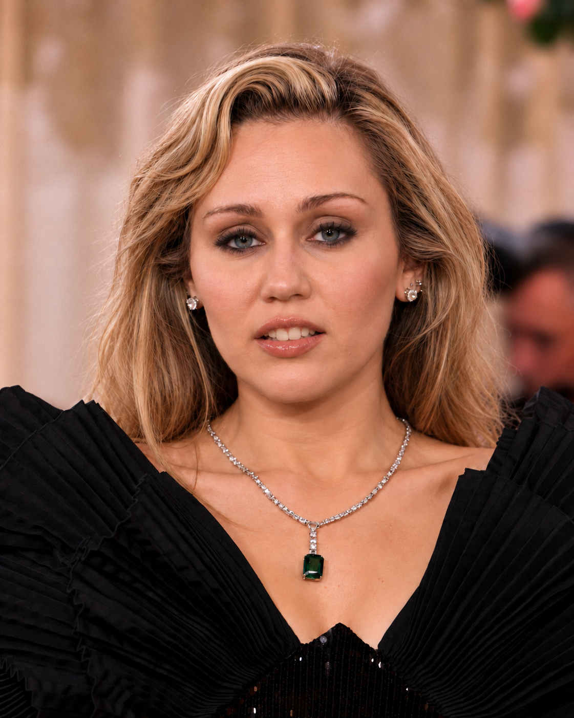 AI-generated image of Miley Cyrus facing the camera in a black pleated dress, with blonde hair framing her face and a matching green pendant necklace. | Source: Gemini