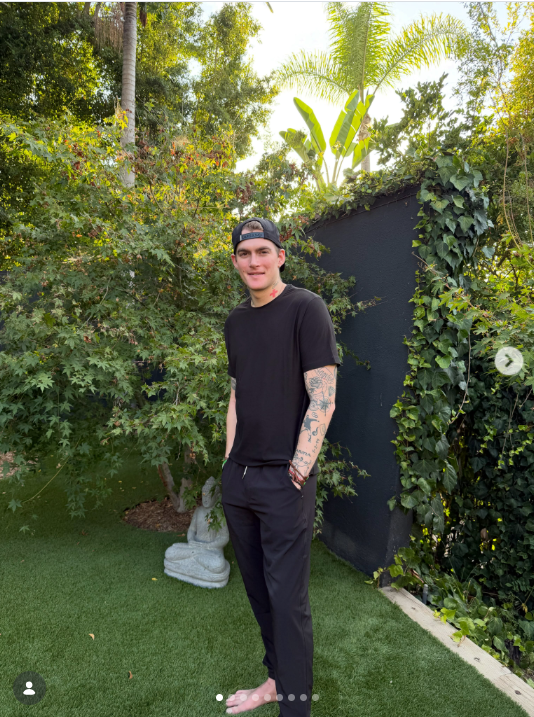 Presley Gerber poses barefoot in a lush garden on August 6, 2026, wearing an all-black outfit and backward baseball cap as he shares a relaxed moment from his life away from public events. | Source: Instagram/presleygerber