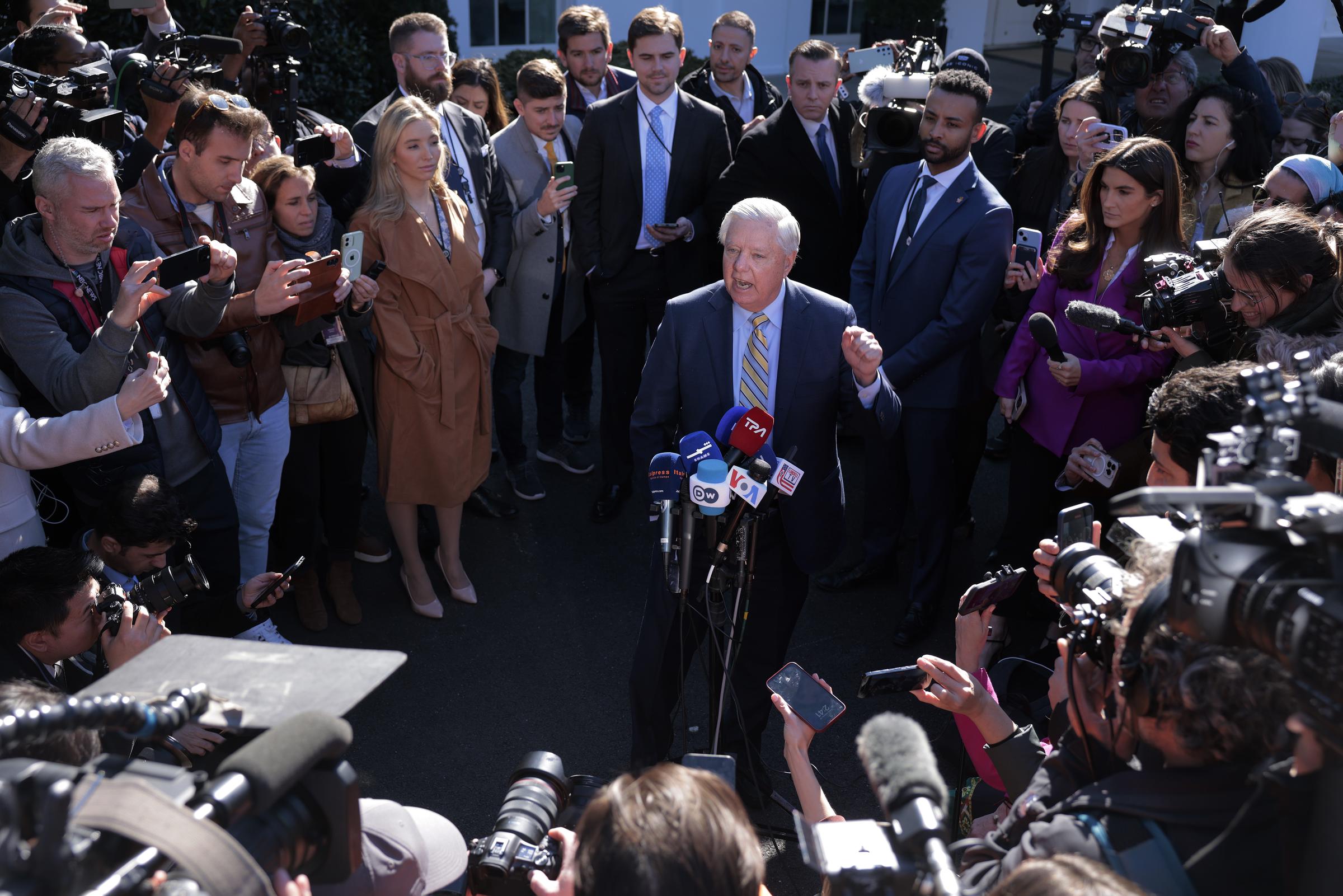 Standing before a crowd of cameras and microphones, Lindsey Graham delivers remarks to reporters outside the West Wing, fielding questions as international developments dominate the political conversation. | Source: Getty Images
